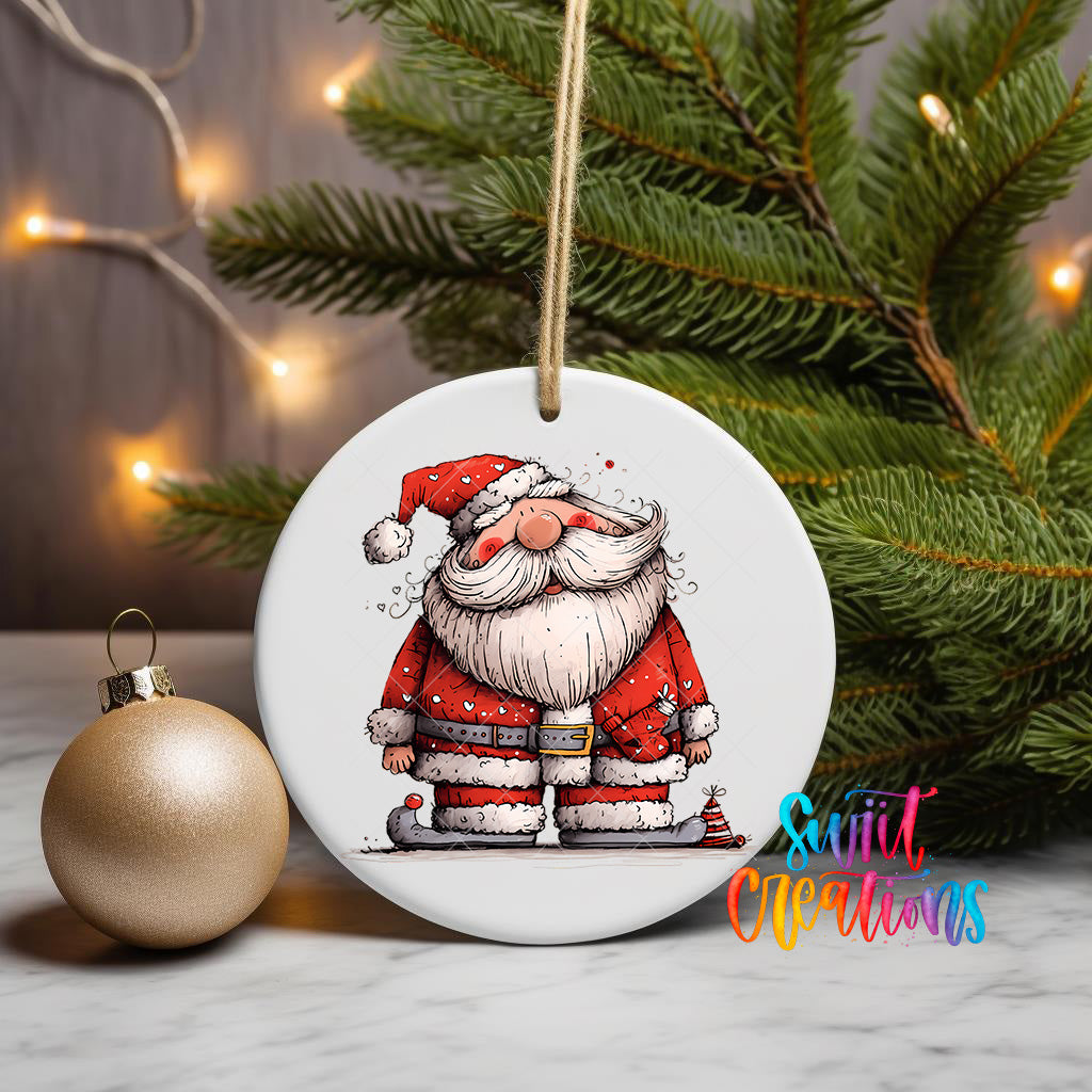 A white ceramic ornament featuring a cartoon Santa Claus figure is displayed on a table, with a gold ornament and a Christmas tree in the background.
