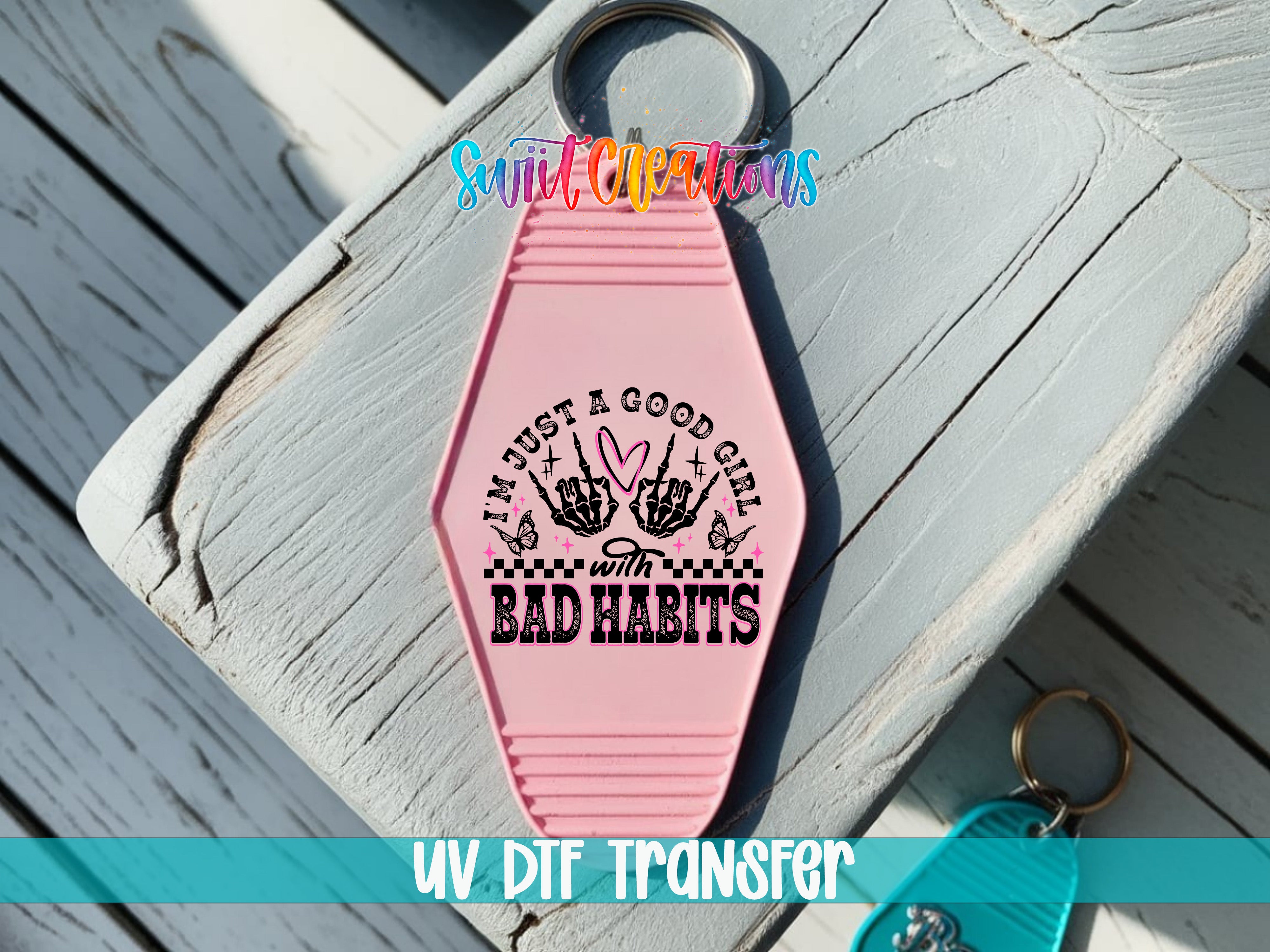 A pink keychain with a message printed on it, placed on a wooden surface.