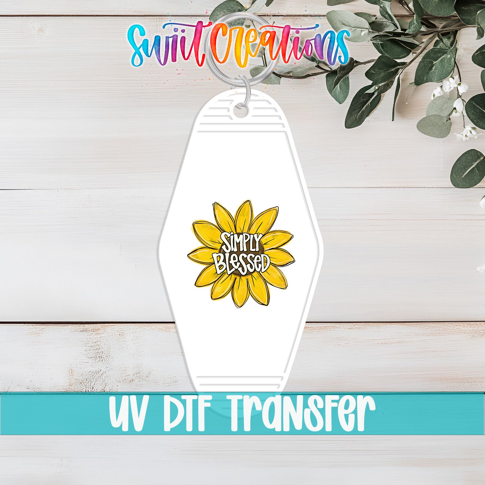A keychain with a yellow flower design and the text "Simply Blessed" printed on it, placed on a wooden surface with a plant in the background.