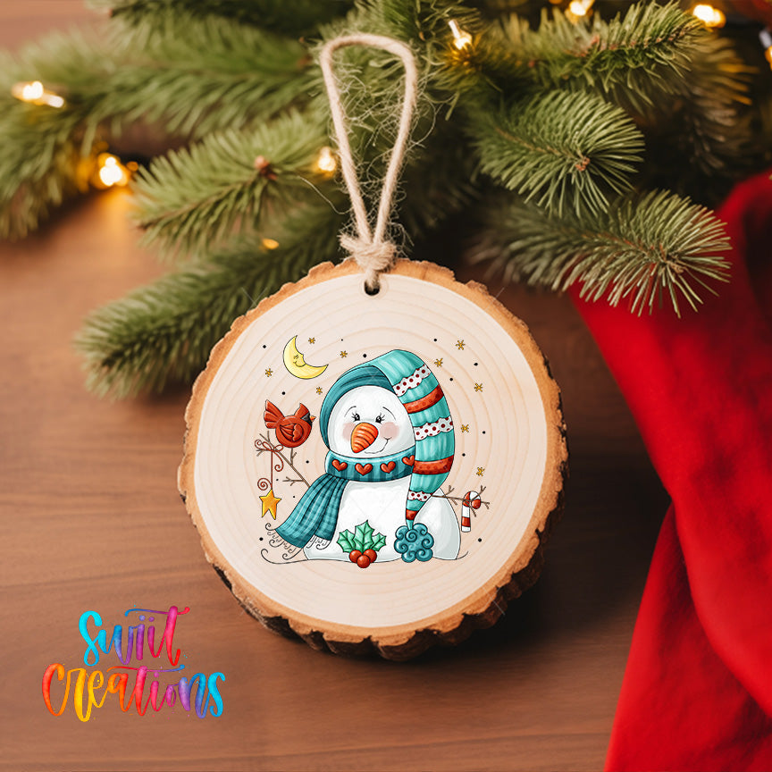 A wooden ornament featuring a snowman with a scarf and hat, surrounded by various winter-themed elements such as pine branches, stars, and a bird.