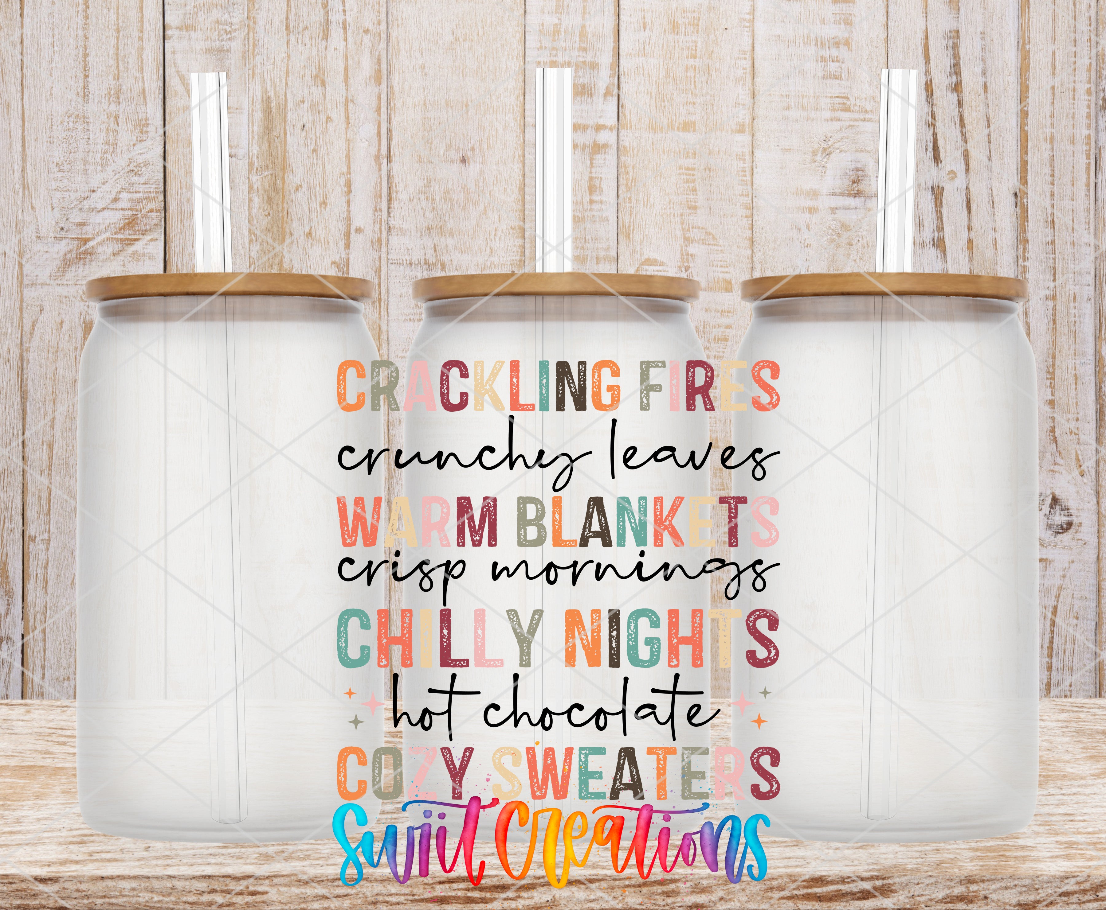 three glass jars with lids, arranged in a row against a wooden background. The jars have straws sticking out of the lids. The text in the image is colorful and includes phrases such as "CRACKLING FRES", "CRUNCHY LEAVES", "WARM BLANKTS", "CRISP Mornings", "CHILLY NIGHTS", "HOT CHOCOLATE", "COZY SWEATERS", and "SWEET CREATIONS".