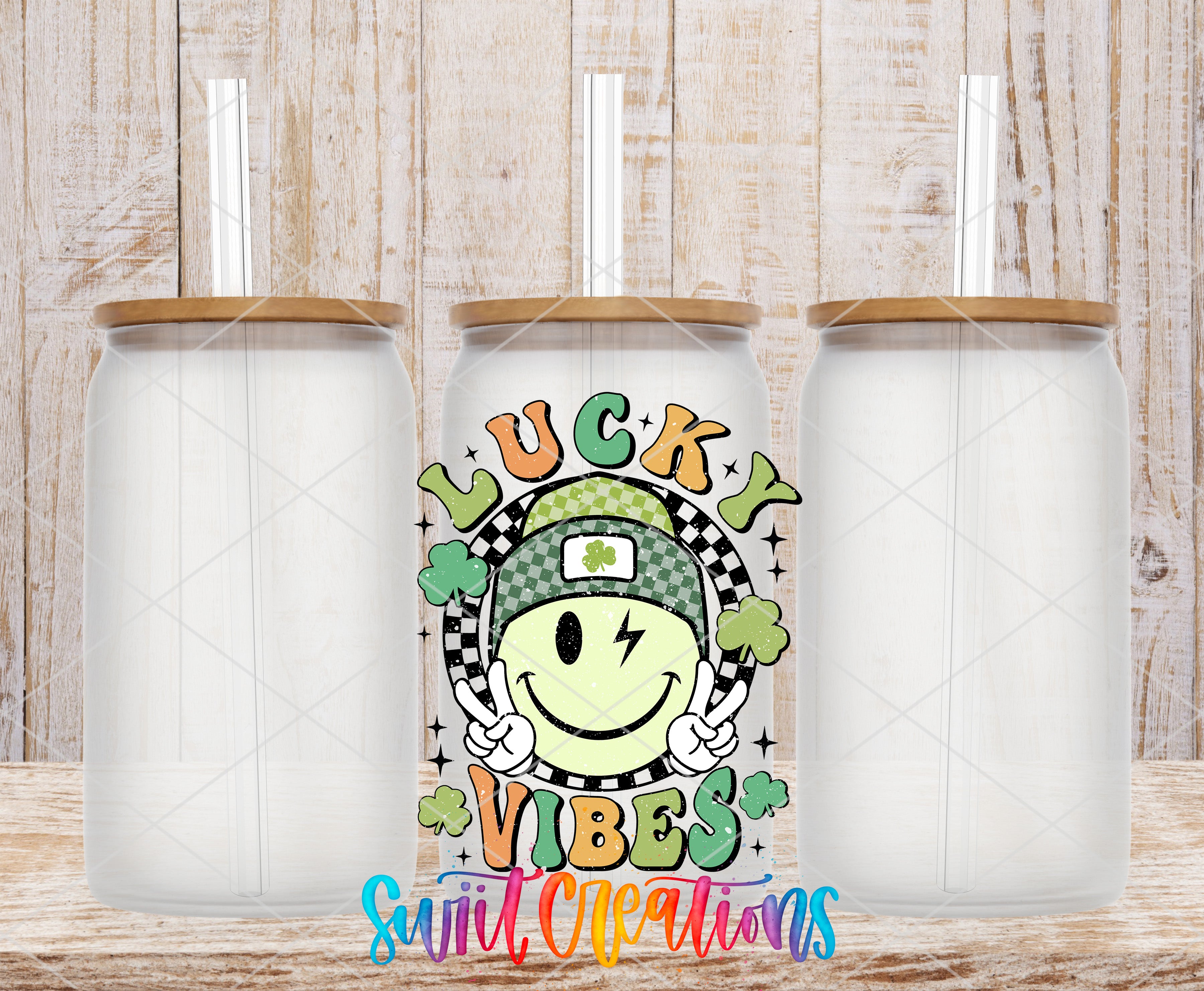 three clear glass tumblers with wooden lids, each with a straw. In the center of the image, there is a tumbler with a smiling face and the text "Lucky Vibes" written on it.