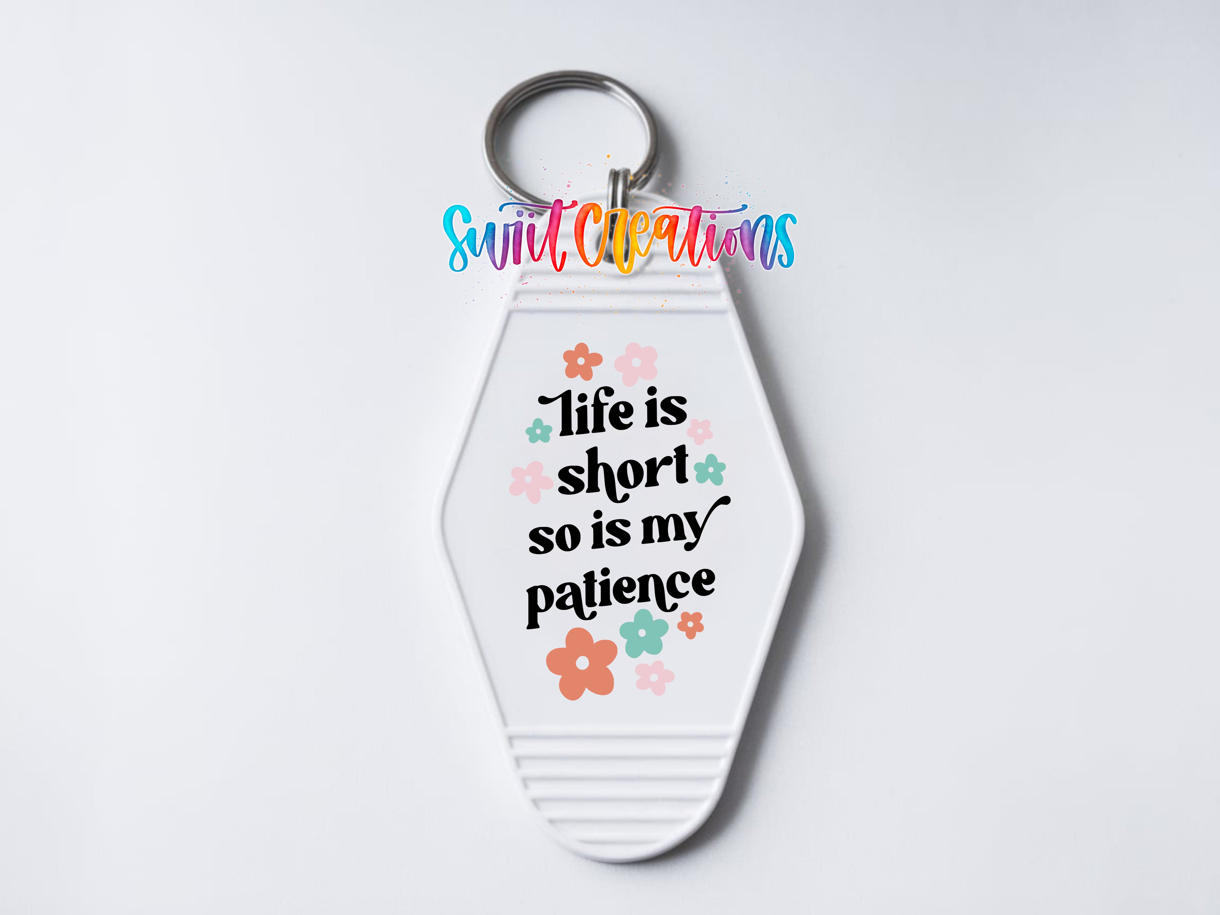 A keychain with a message that reads "Life is short so is my patience" and colorful flower designs surrounding it.
