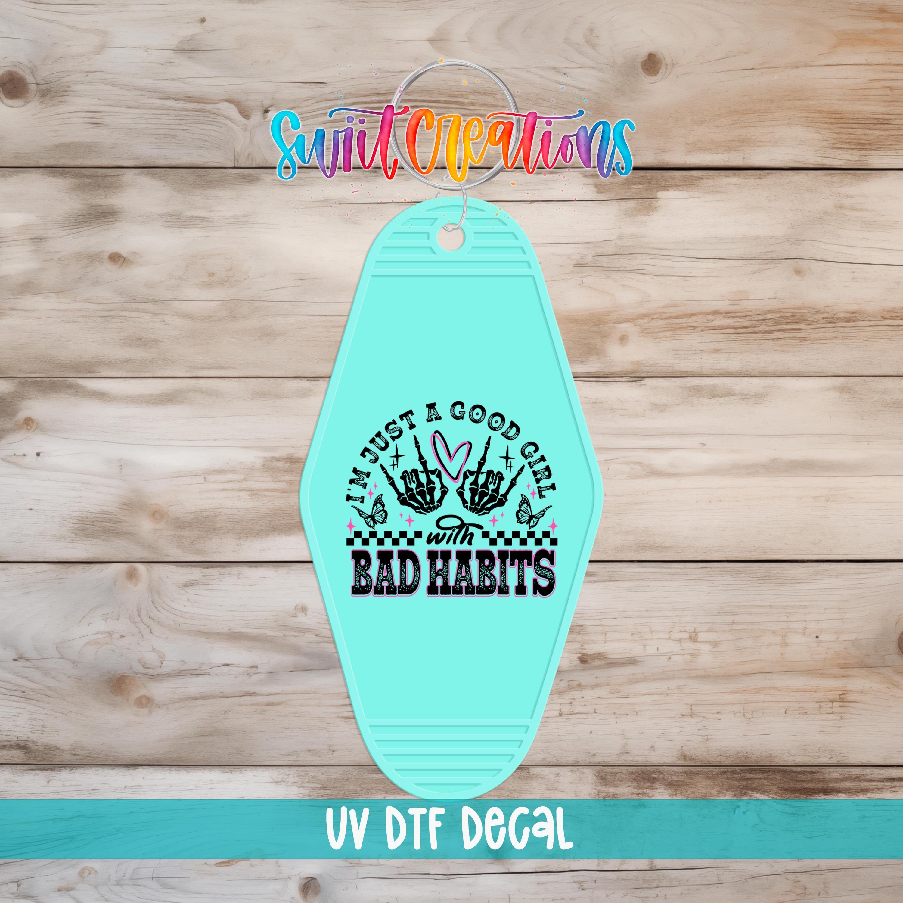 A turquoise keychain with a graphic design and text on it, placed on a wooden surface.