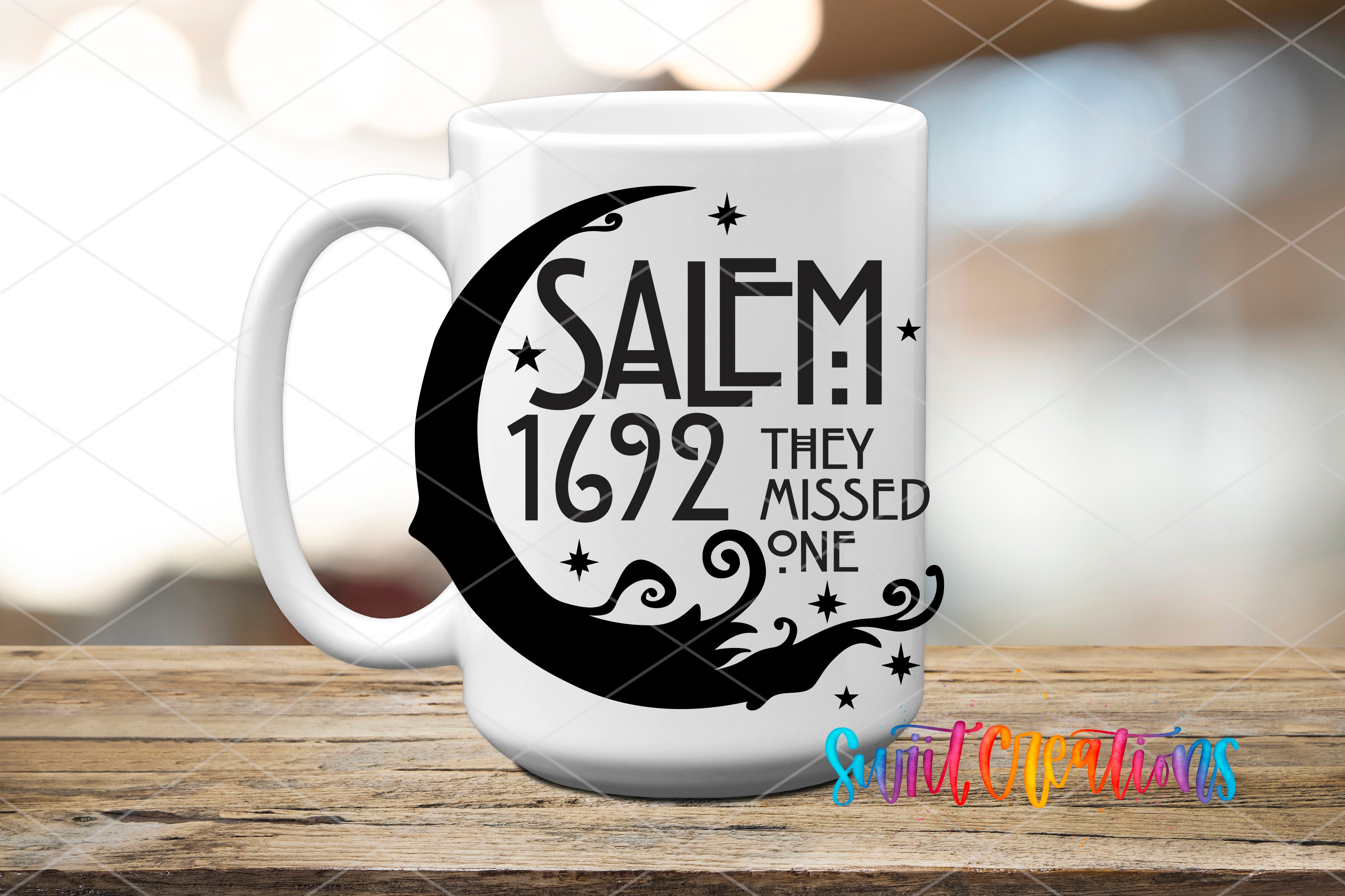 A white mug with a black design featuring a crescent moon and stars, along with the text "SALEM 1692 THEY MISSED ONE" printed on it.