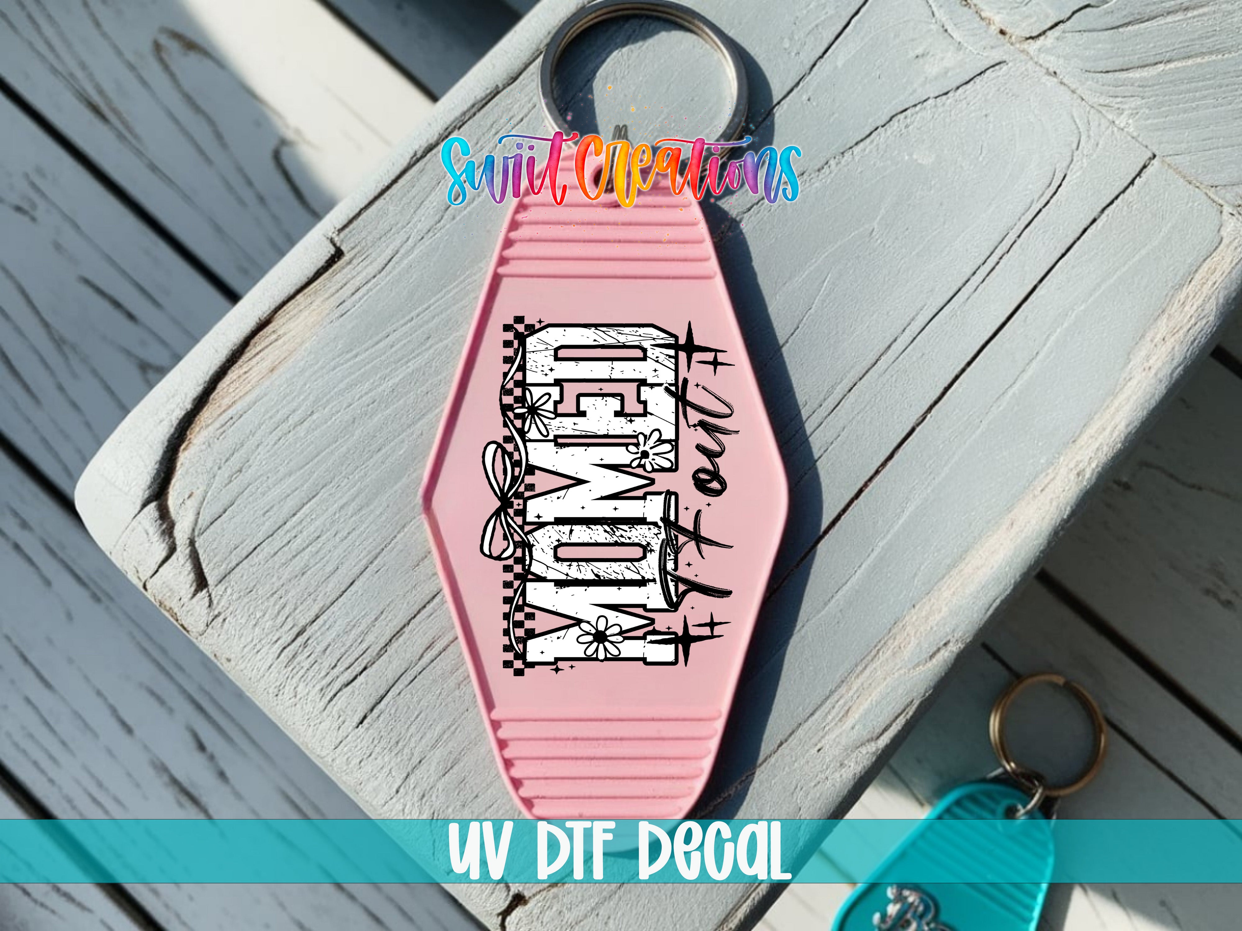 A pink keychain with the word "DOG" printed on it, placed on a wooden surface.