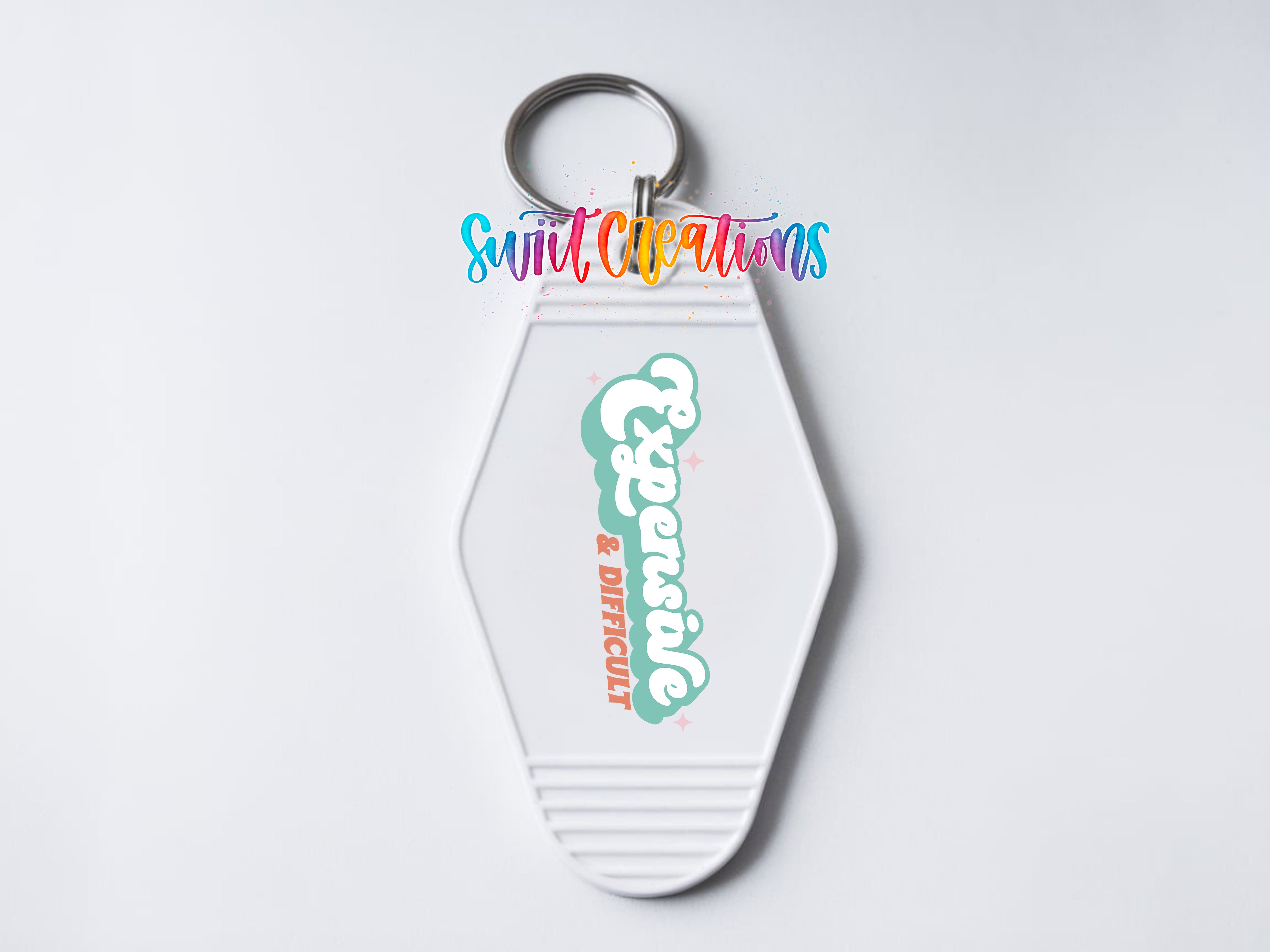 A white keychain with a colorful design and text on it.