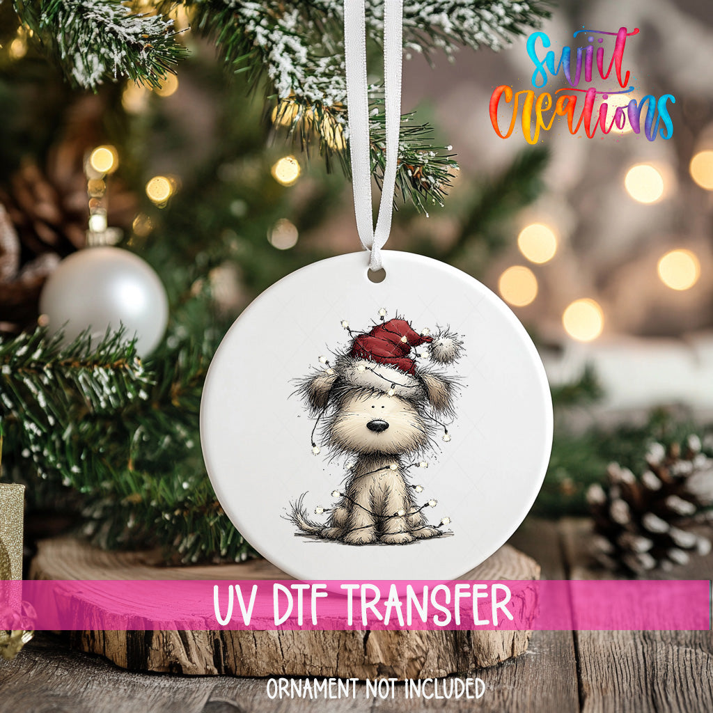 A white ornament with a dog wearing a Santa hat is hanging on a Christmas tree.