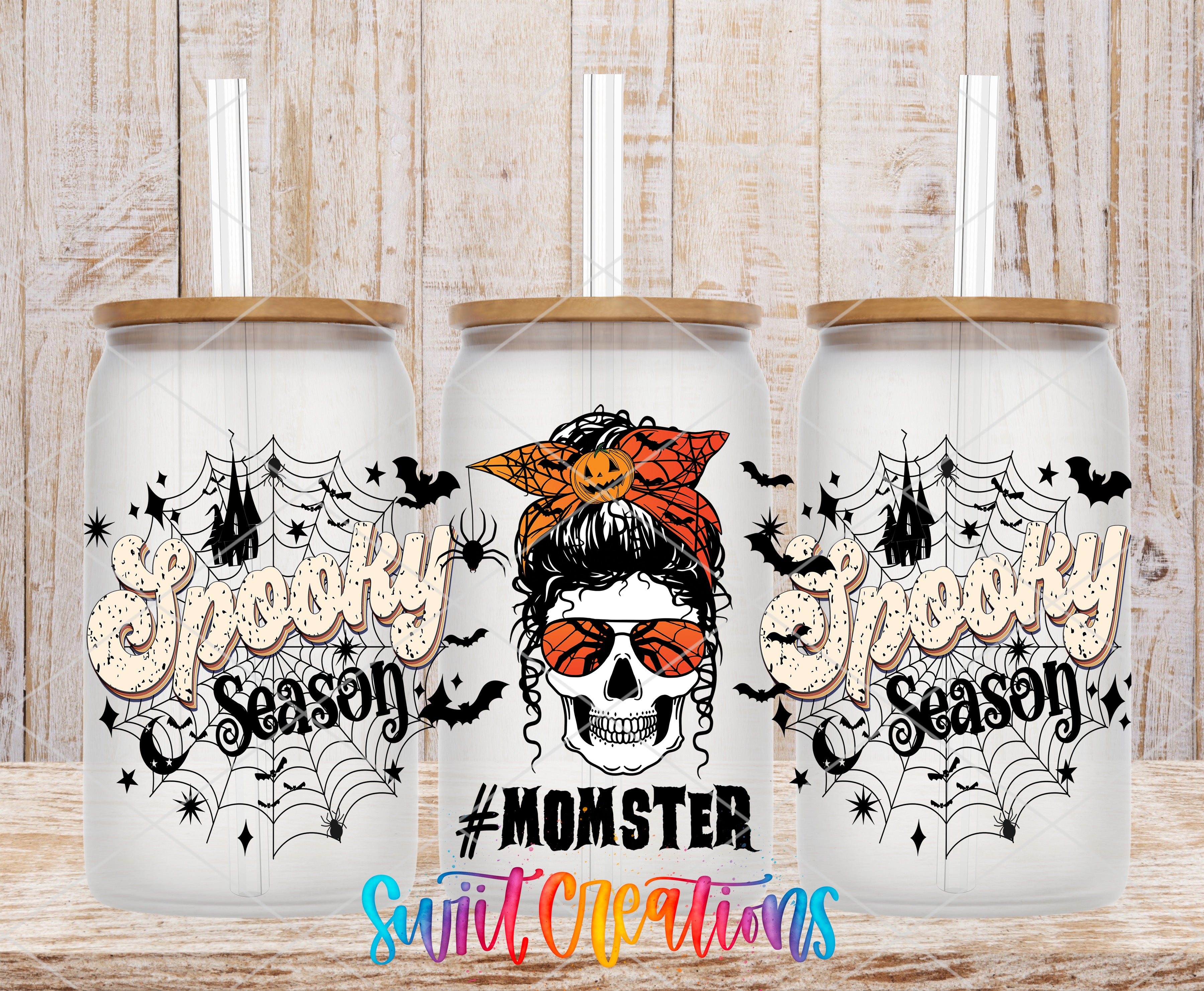 three glass tumblers with Halloween-themed designs, including a skull wearing sunglasses and a spider web.
