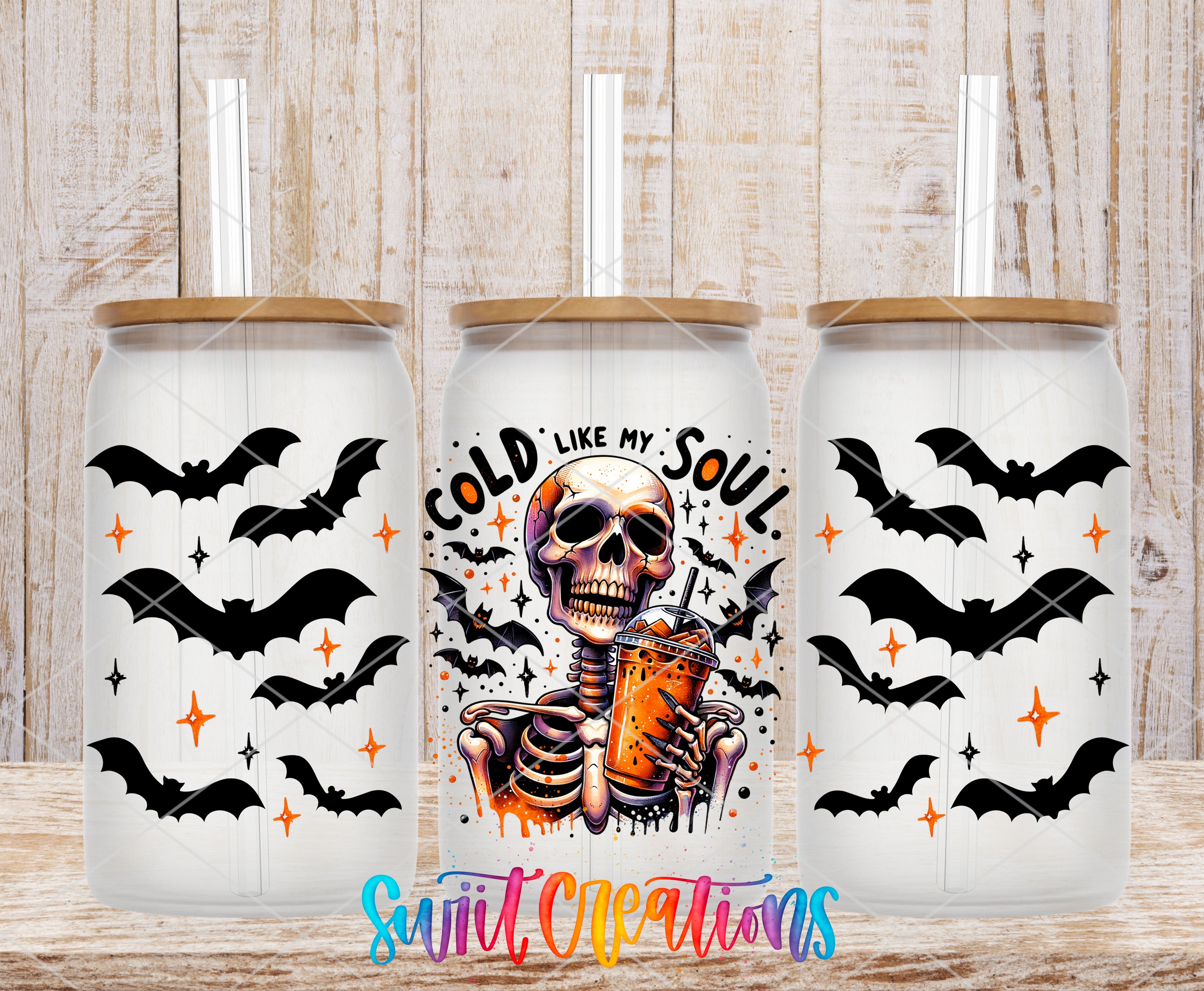 three glass tumblers with a Halloween-themed design. The tumblers have a skull and bats motif, and one tumbler has a drink in it. The text on the tumbler reads "GOLD LIKE MY SOUL" and "Swift Creations".