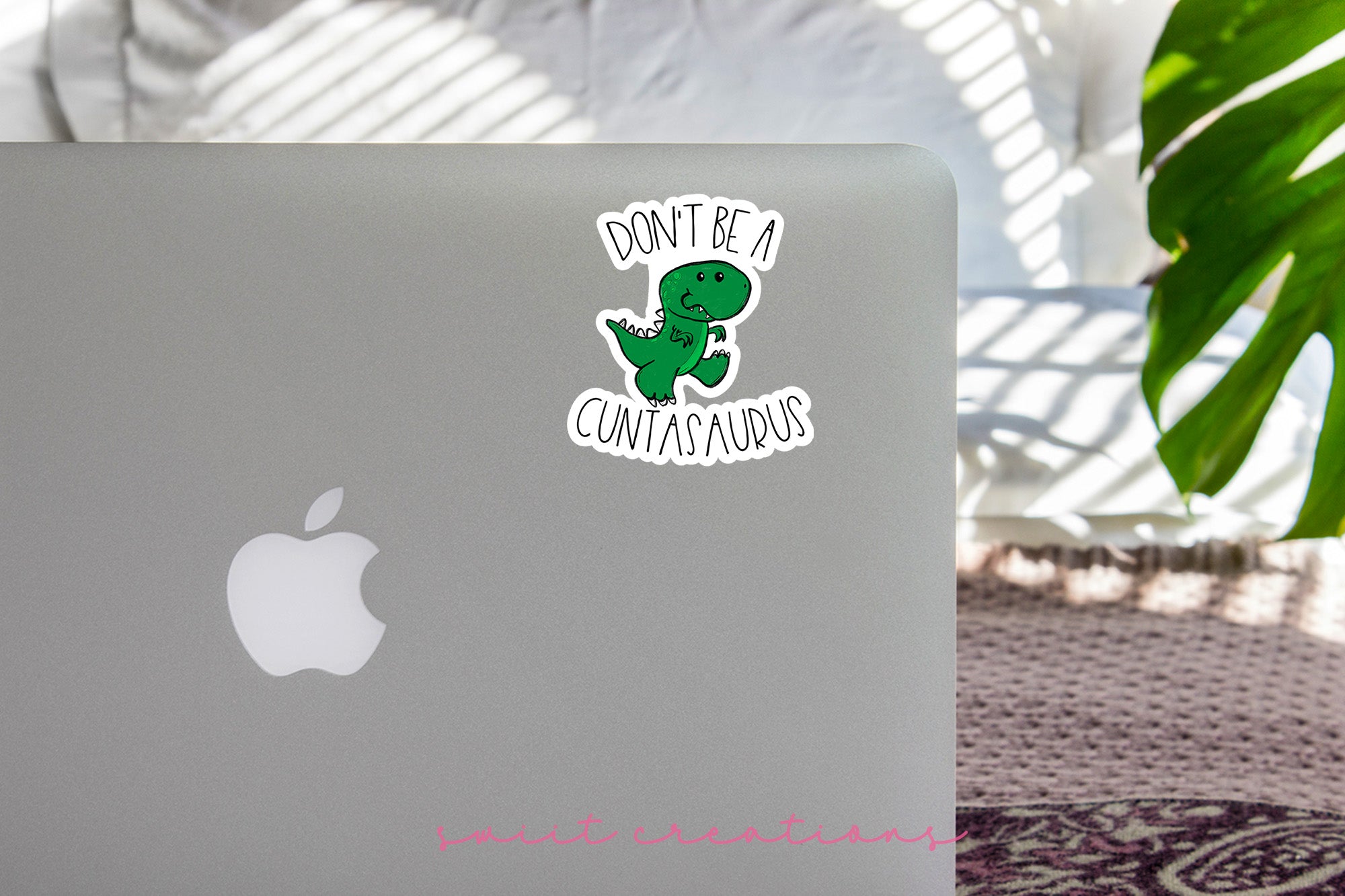 a laptop with a sticker of a dinosaur on it