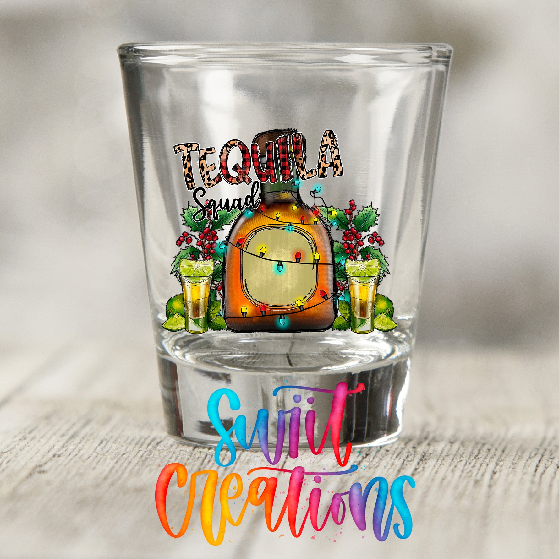 A shot glass with a tequila-themed design, featuring a bottle of tequila, a lime, and a cocktail glass with a tequila-based drink.