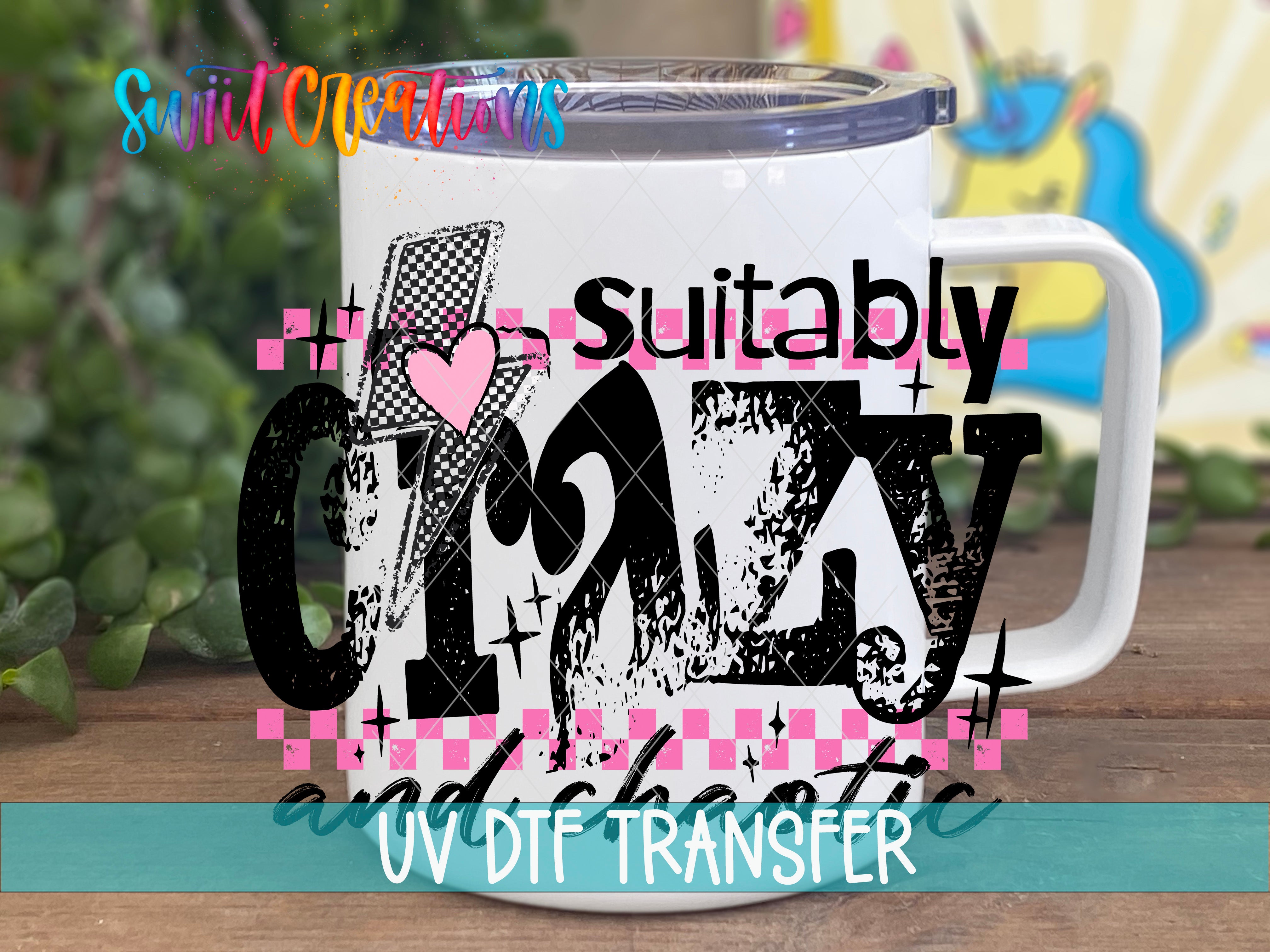 A white mug with a colorful, stylized design featuring the text "suitable crazy" and "UV DFT Transfer" printed on it.