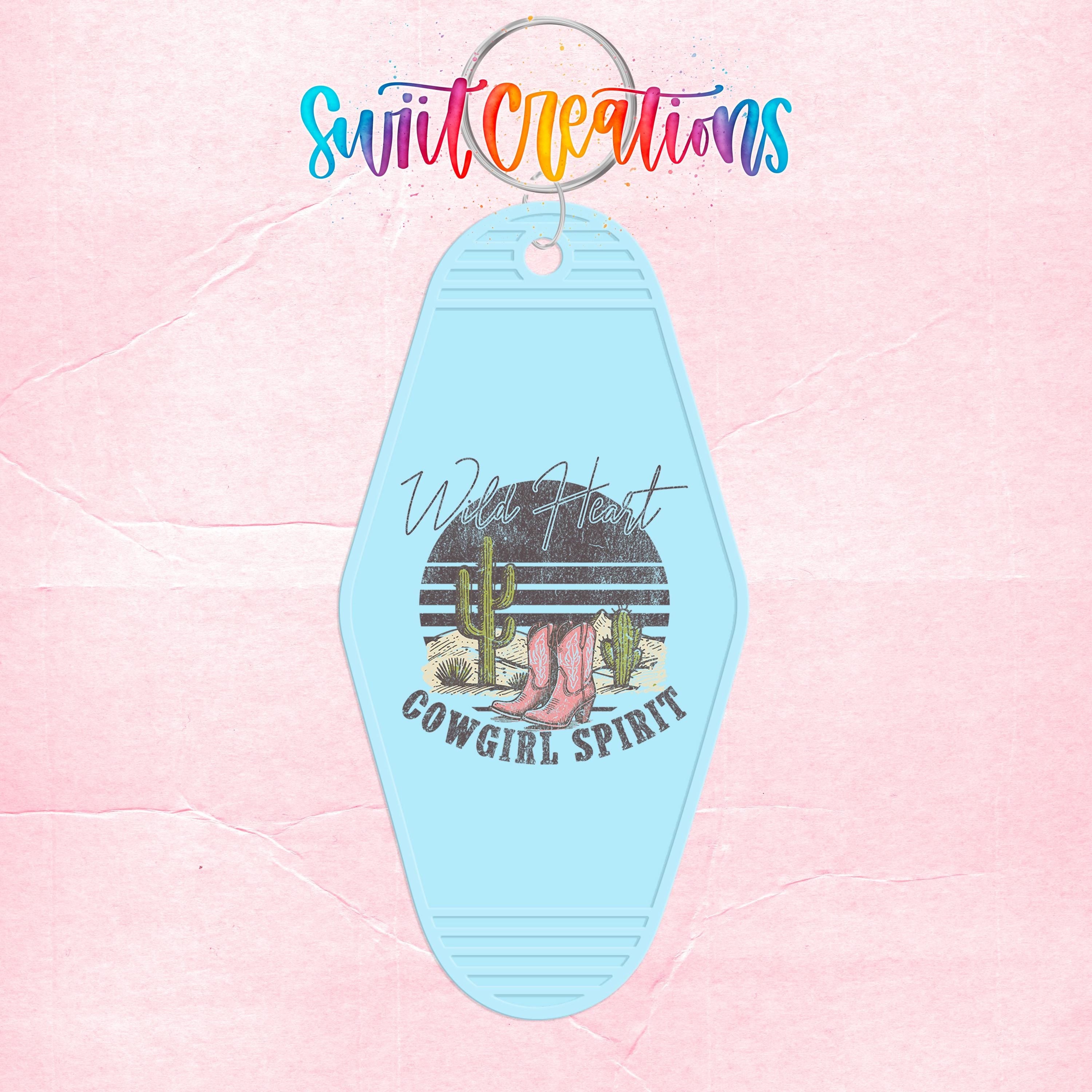 A keychain with a blue design featuring a cowboy hat, cactus, and the text "Wild Heart Cowgirl Spirit".