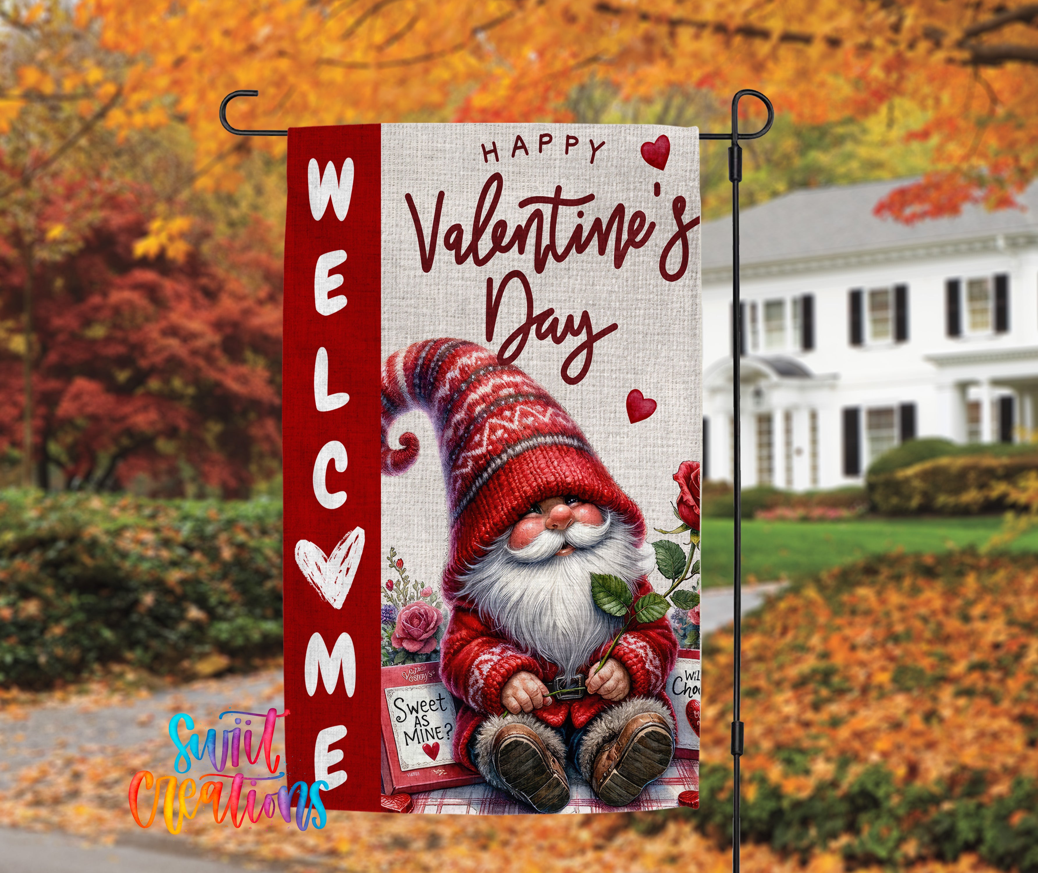 A red and white welcome sign with a gnome holding a rose and a heart, set against a backdrop of autumn foliage and a white house.