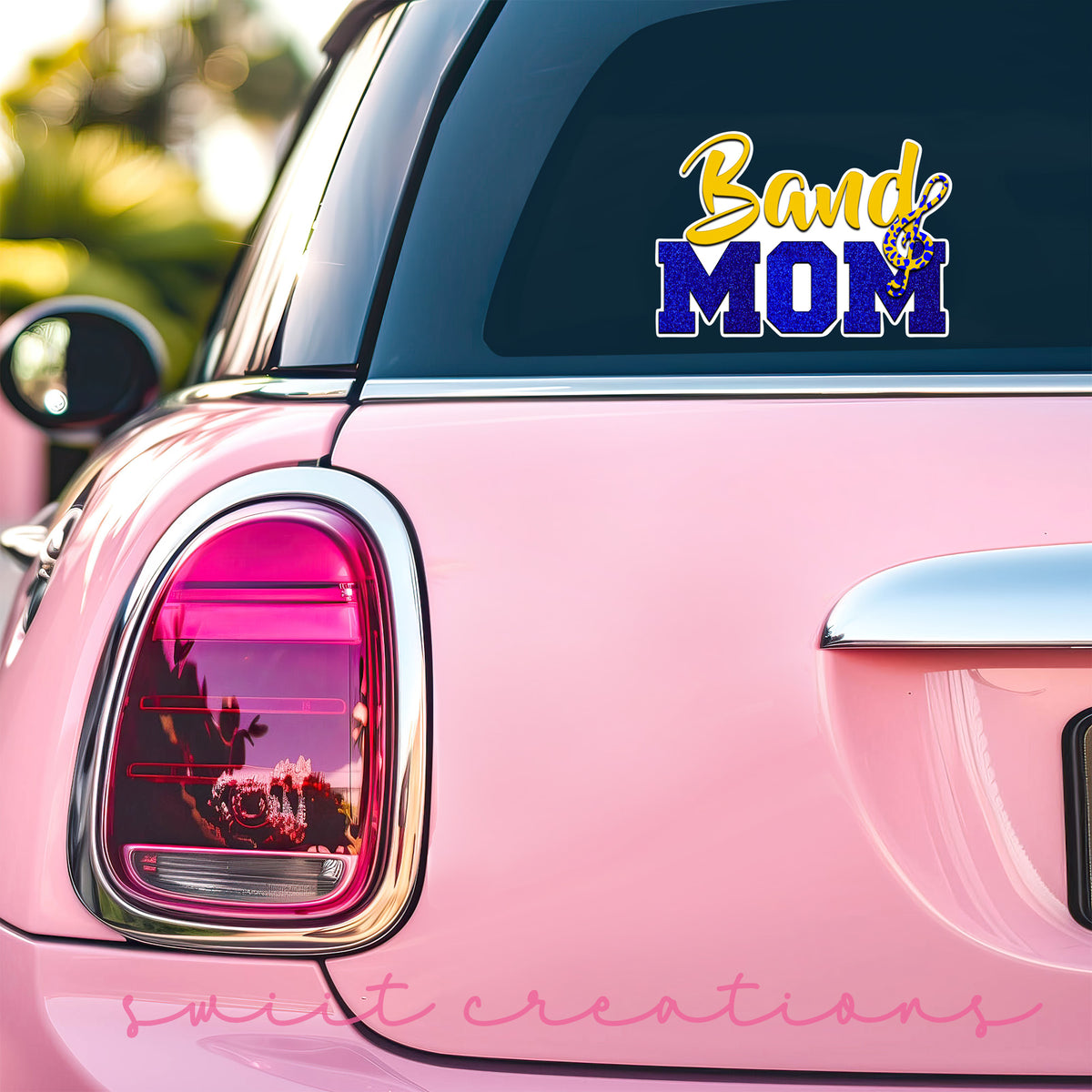 Gold and Blue Band Mom sticker on the back window of a pink car