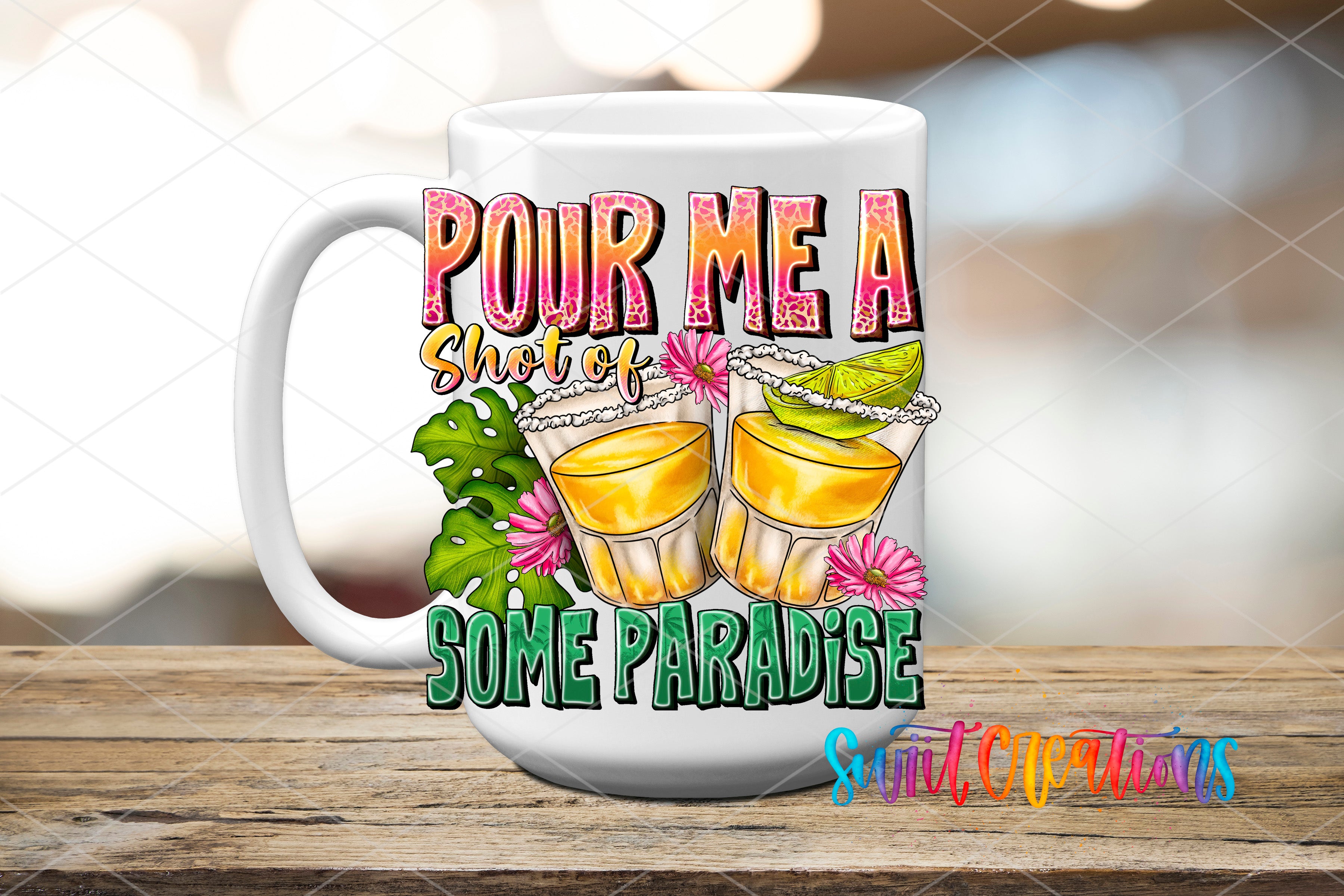 A white mug with a colorful graphic design featuring two glasses of tequila with lime slices, surrounded by tropical plants and flowers, along with the text "POUR ME A SHOT OF SOME PARADISE" and "Suit Creations".