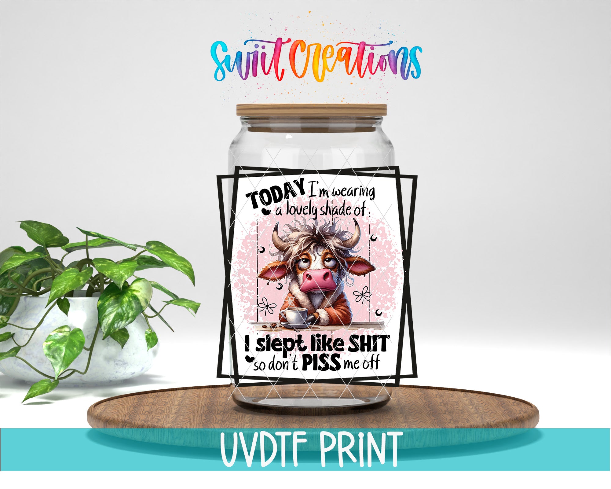 A jar with a label featuring a cartoon cow and text, placed on a wooden surface next to a potted plant.