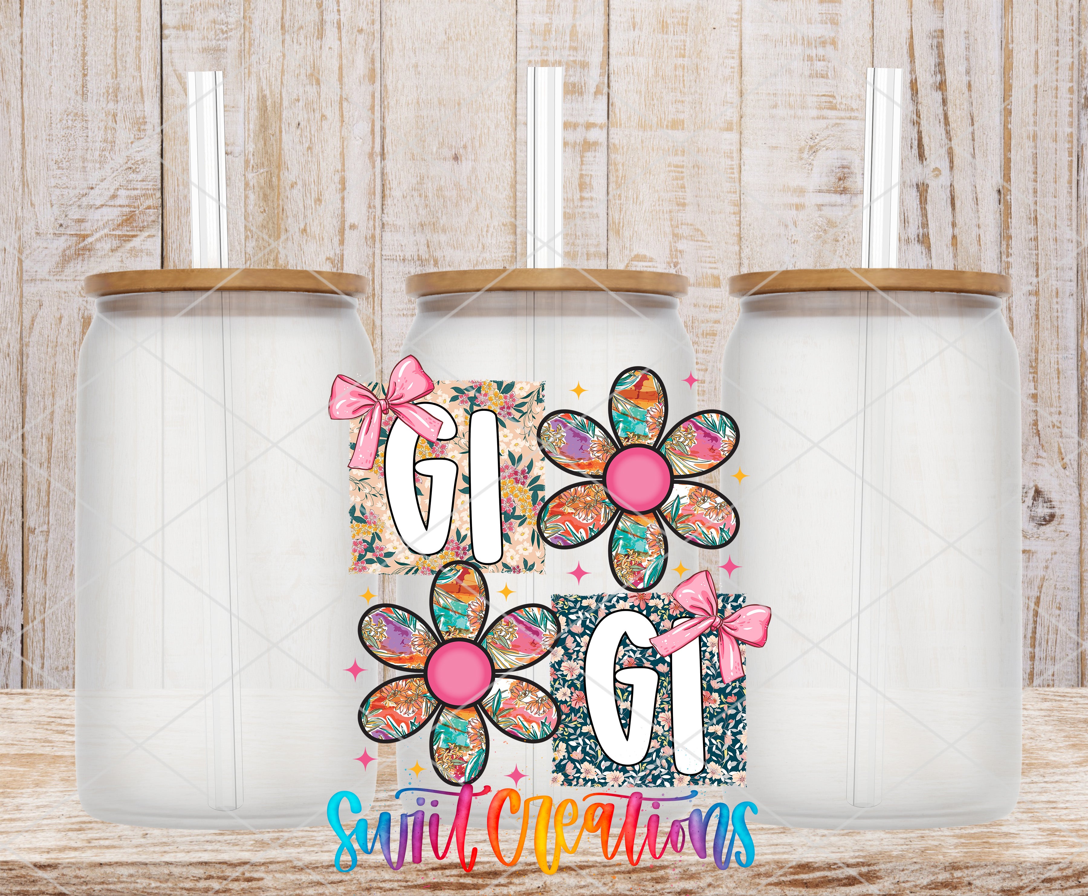 three glass jars with flower designs and straws, arranged in a row against a wooden background.