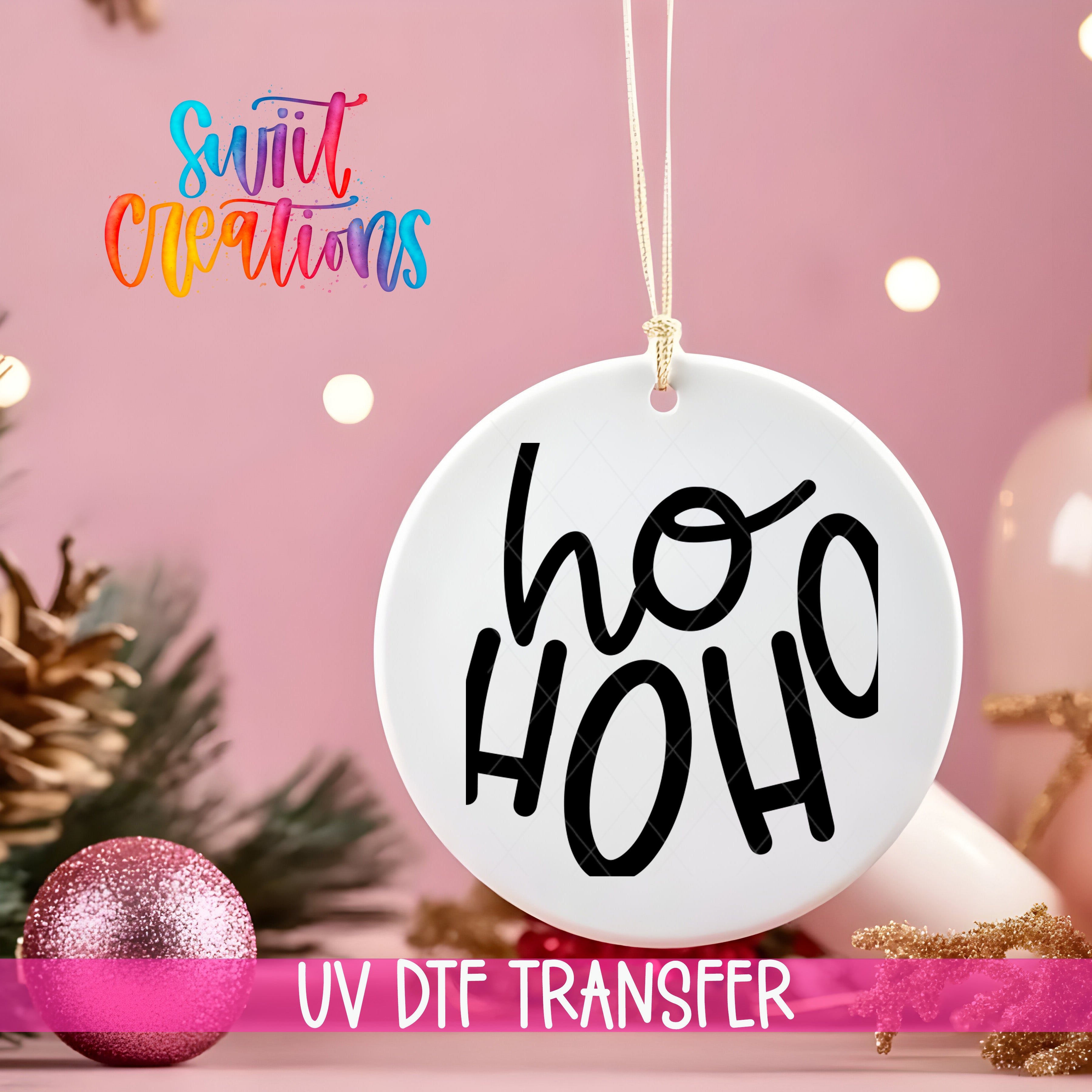 A white ornament with the text "ho ho ho" in black letters is hanging on a string against a pink background, with Christmas decorations and a pink glitter ornament visible in the background.