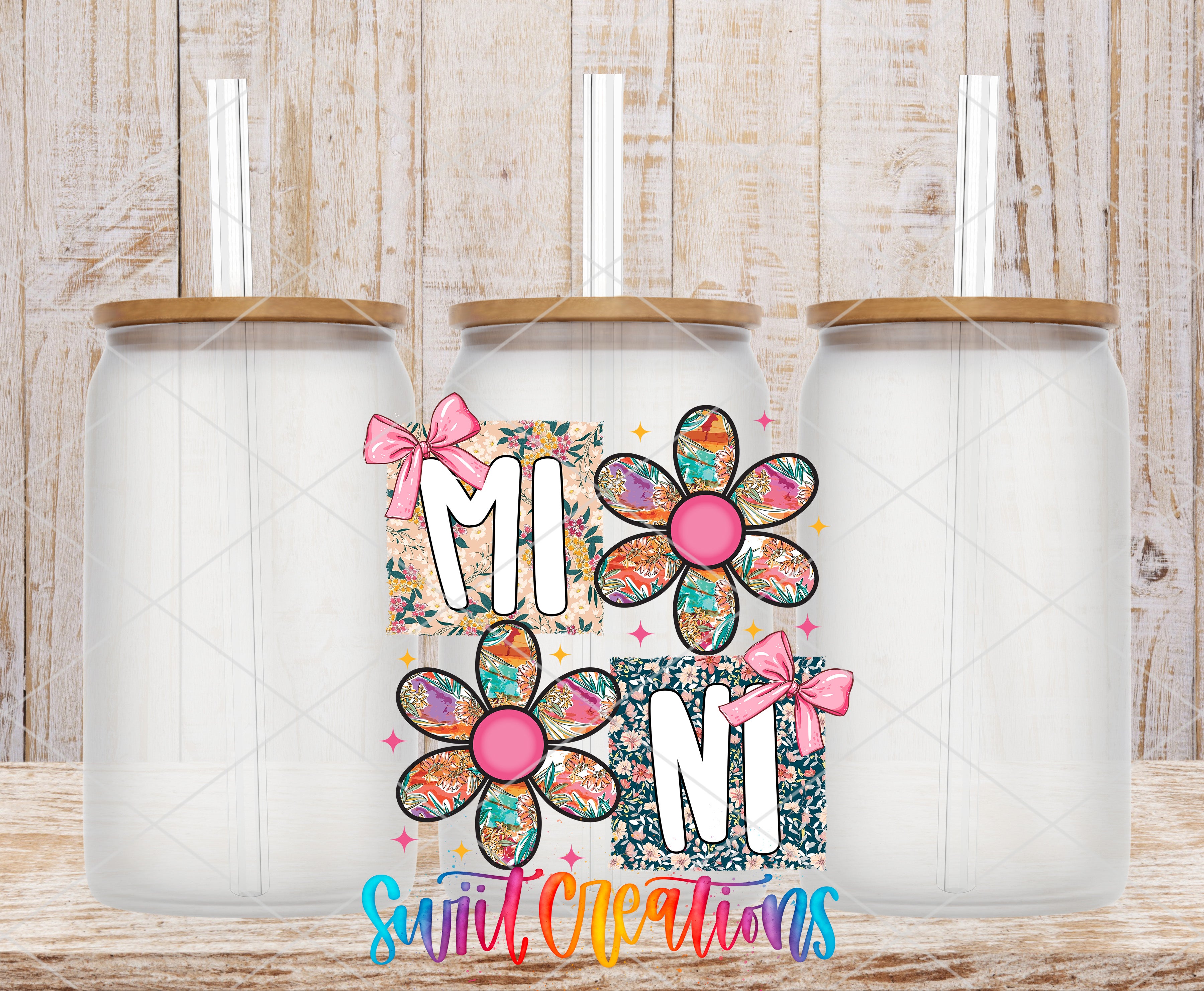 three glass jars with flower designs and straws, arranged in a row against a wooden background.