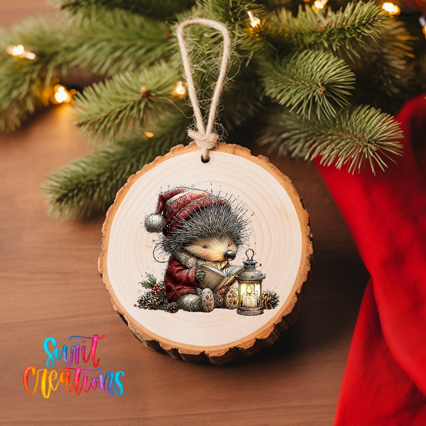 A wooden ornament featuring a hedgehog wearing a red hat and holding a lantern, with a Christmas tree in the background.