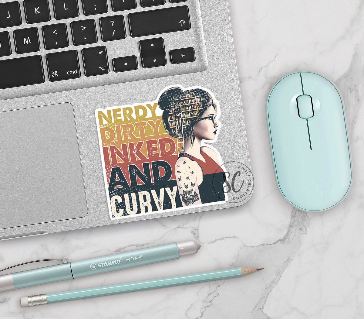 Nerdy Dirty Inked and Curvy vinyl sticker on a silver laptop next to a mint mouse and pens