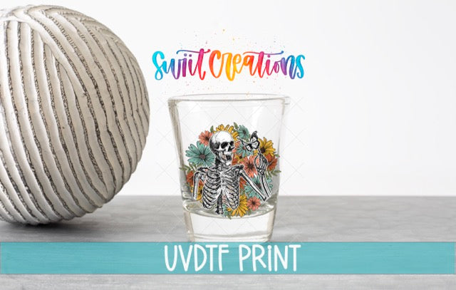 a ball of yarn next to a shot glass