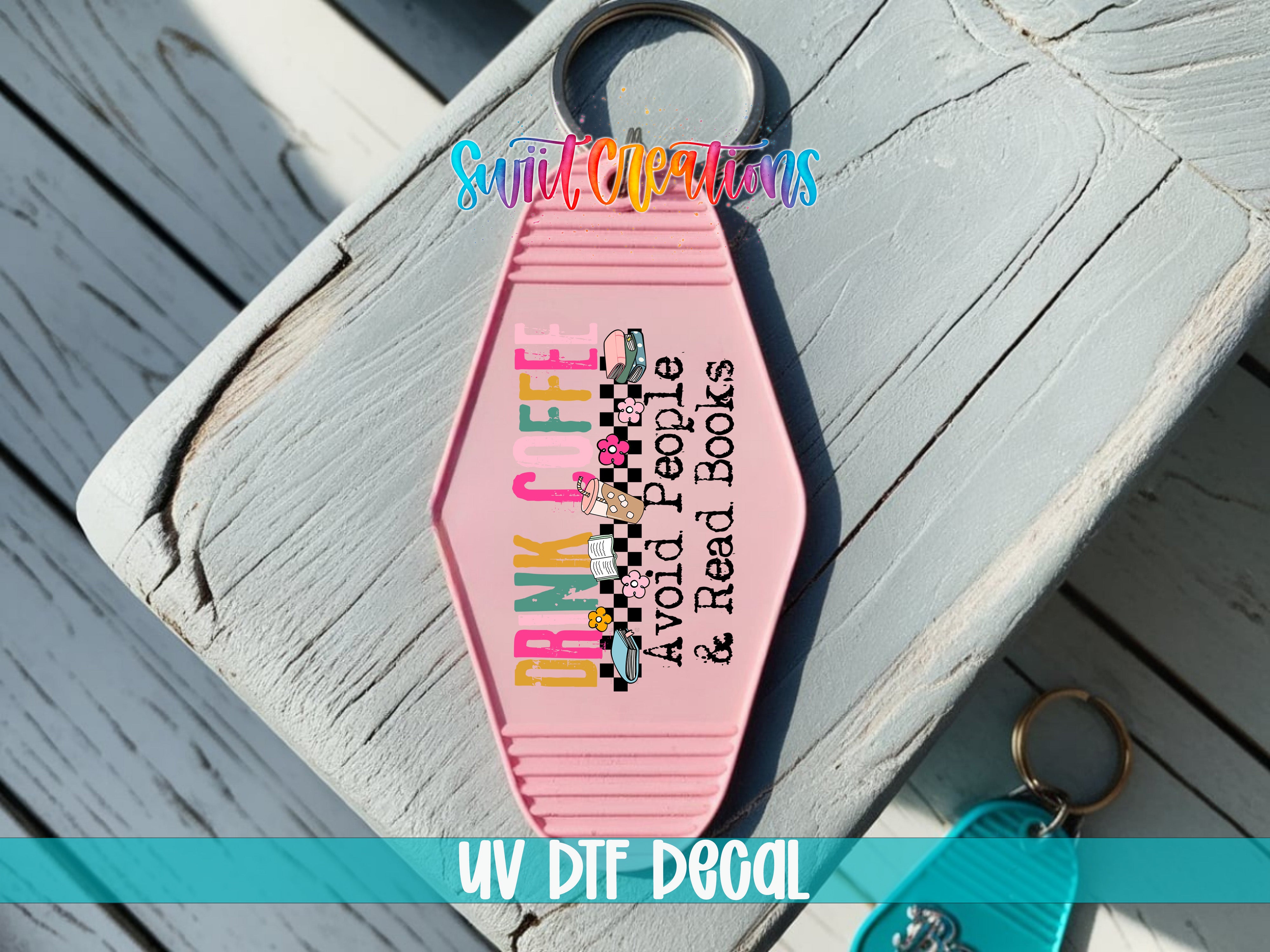 A pink keychain with a message printed on it, placed on a wooden surface.