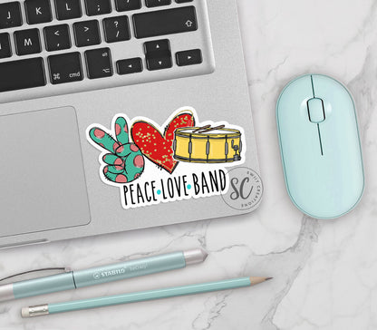 Peace Love Band vinyl sticker on a silver laptop next to a mint mouse and pens