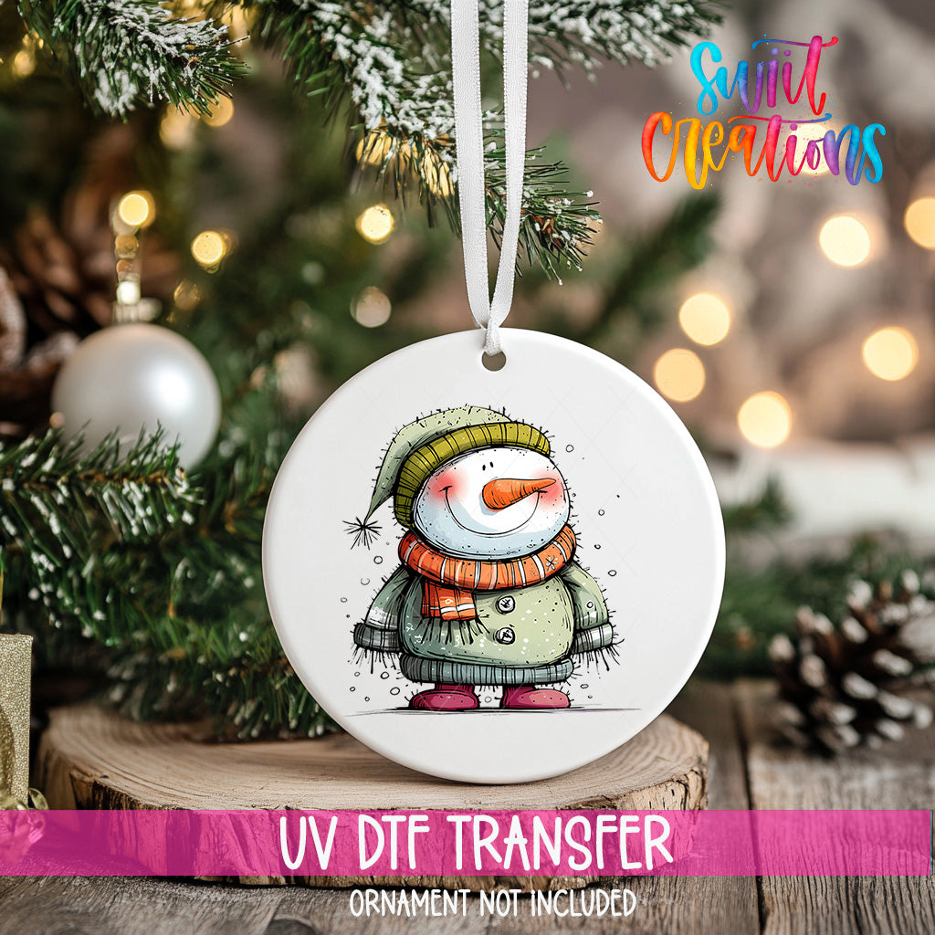 A white ceramic ornament featuring a snowman is hanging on a Christmas tree, with a blurred background of pine branches and twinkling lights.