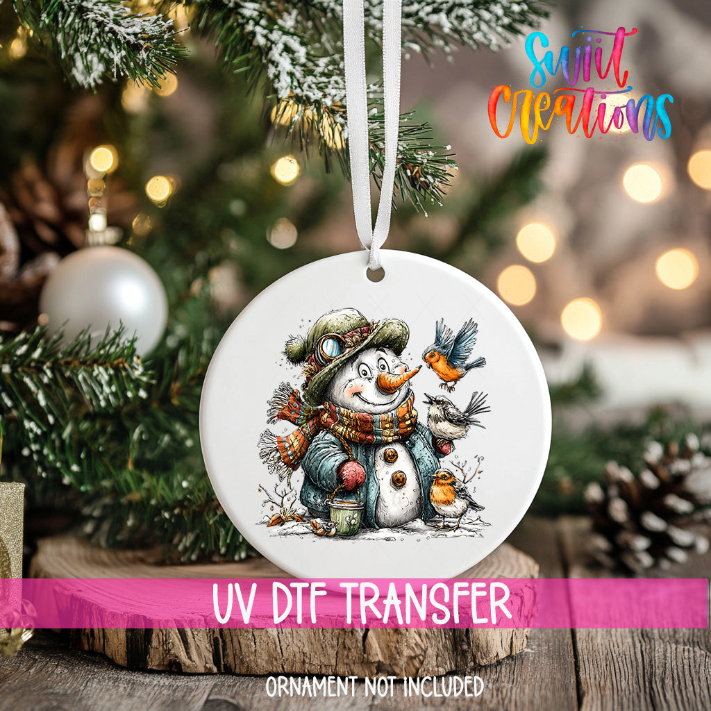 A white ornament with a snowman and birds on a snowy background, hanging on a Christmas tree.