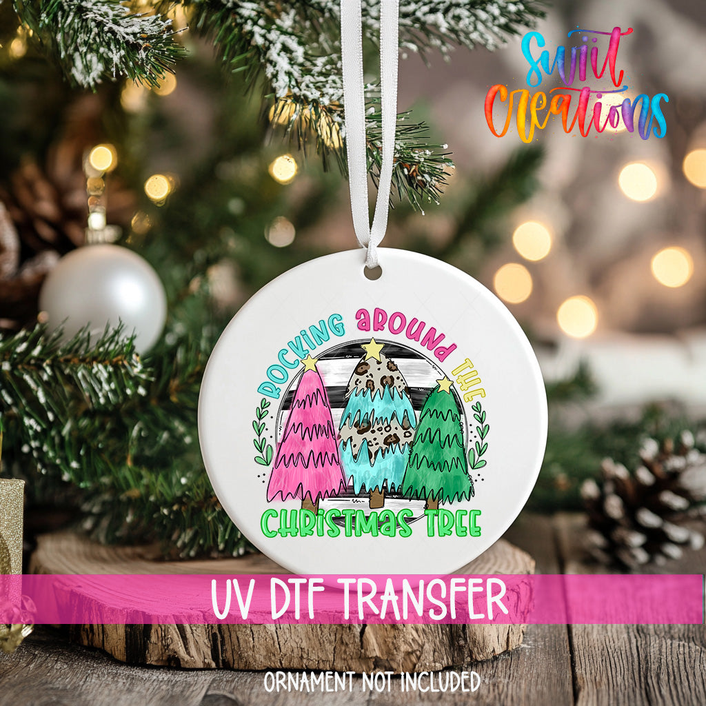 A white ceramic ornament with a colorful design hangs on a Christmas tree, surrounded by pine branches and twinkling lights.