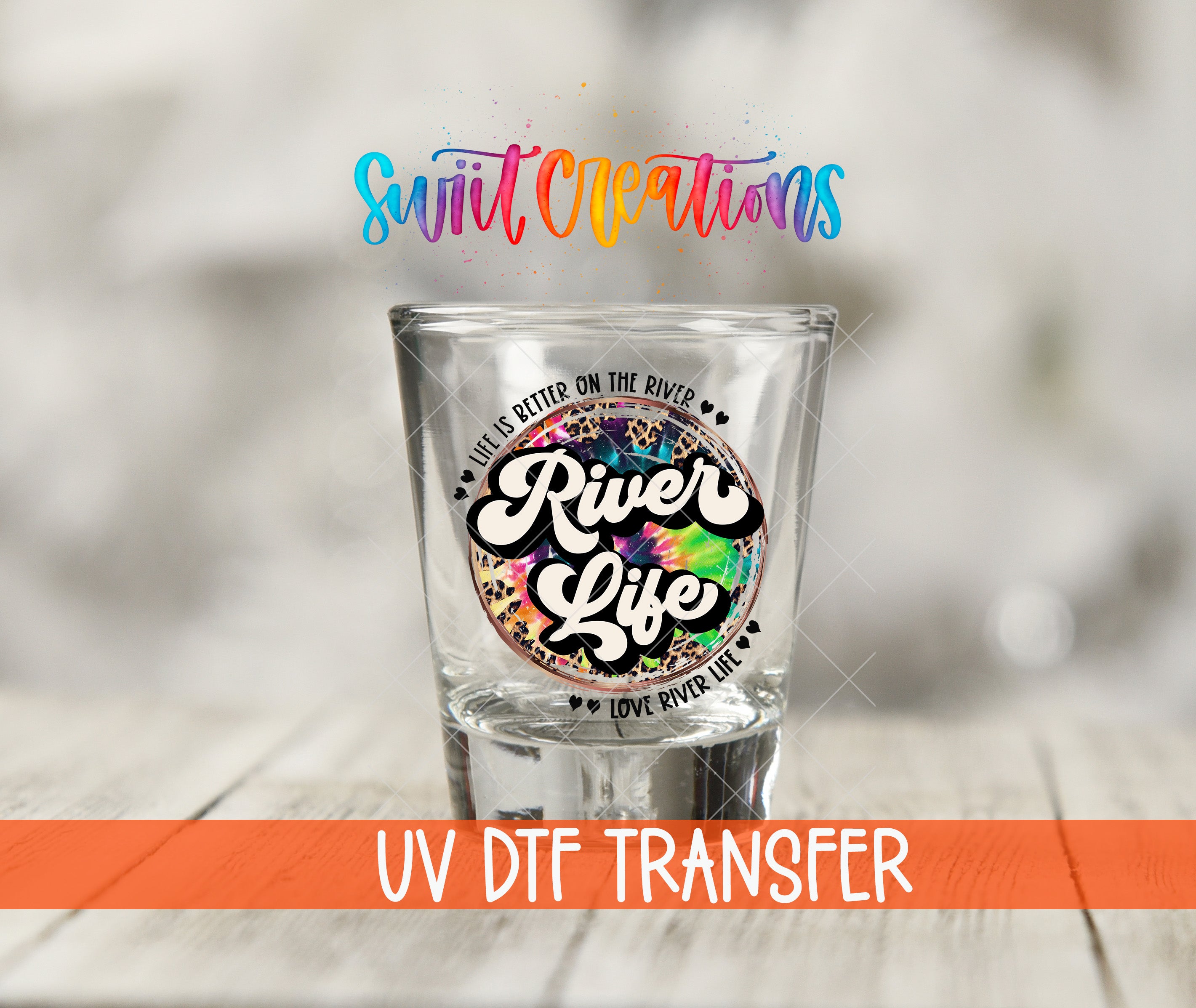 A shot glass with a colorful, tie-dye design and text printed on it, placed on a wooden surface.