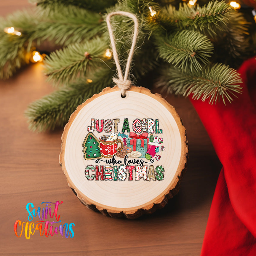 A wooden ornament with a message that says "Just a girl who loves Christmas" hanging on a Christmas tree.