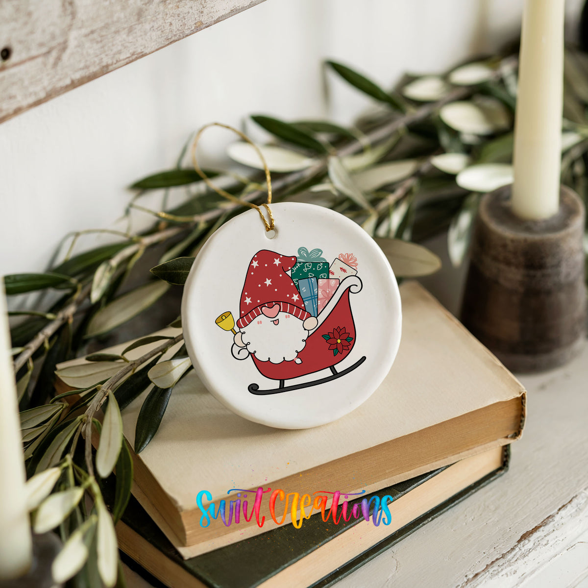 A ceramic ornament featuring a gnome on a sled, surrounded by greenery, placed on top of a stack of books.
