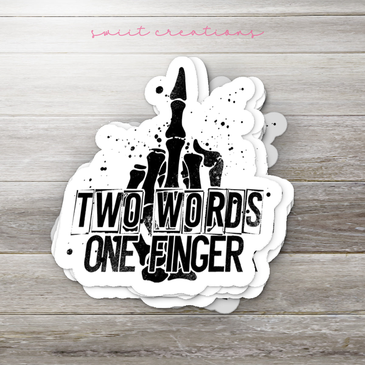 Stack of Two Words One Finger glossy stickers on a gray wood table