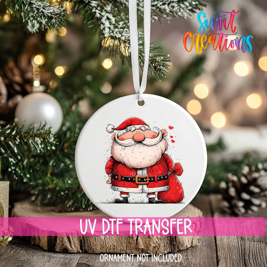 A white ornament with a Santa Claus illustration is hanging on a Christmas tree.