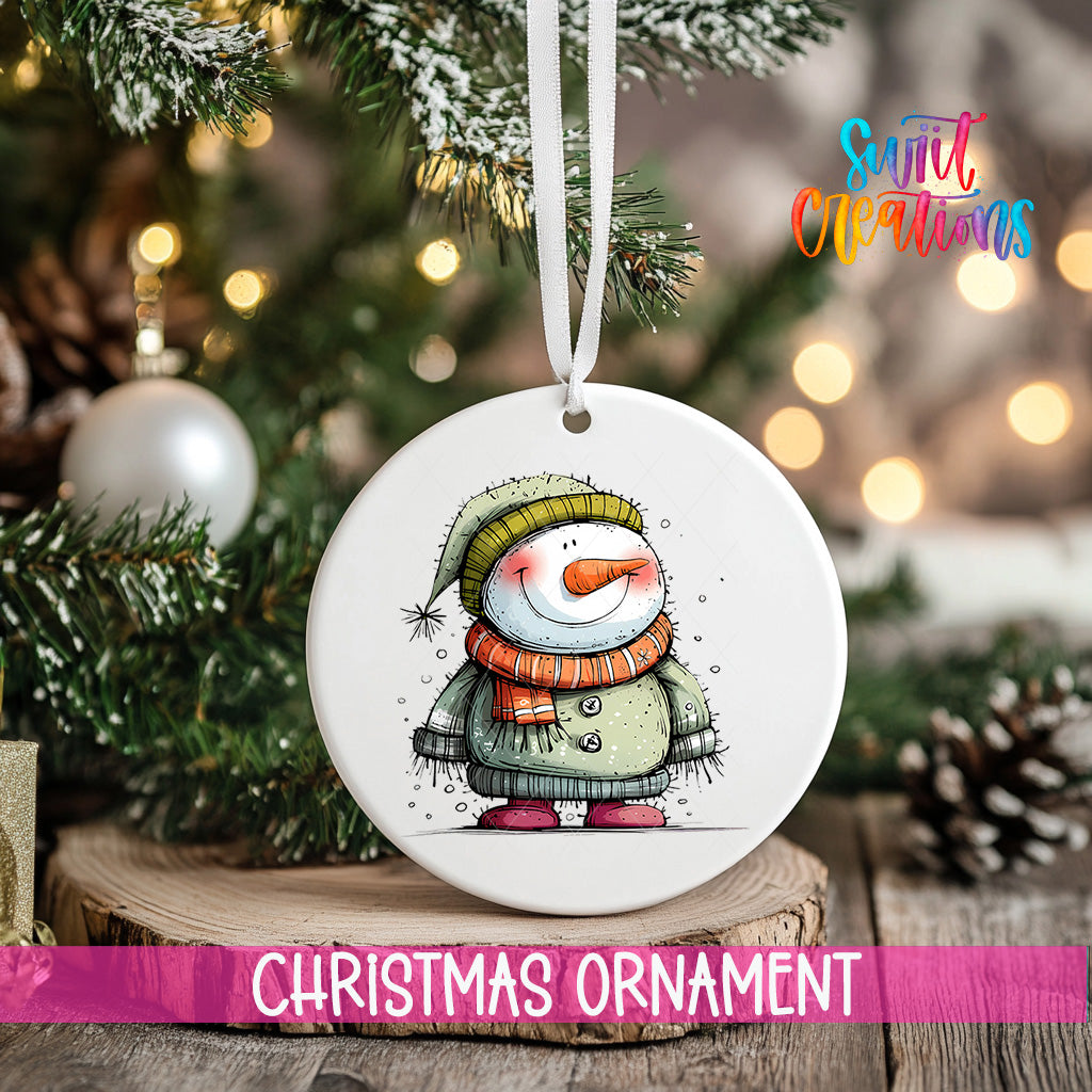 A white Christmas ornament featuring a snowman is hanging from a ribbon, with a blurred background of a decorated Christmas tree and other ornaments.