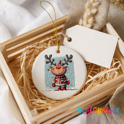 A white ceramic ornament with a reindeer design is displayed in a wooden crate, surrounded by straw.