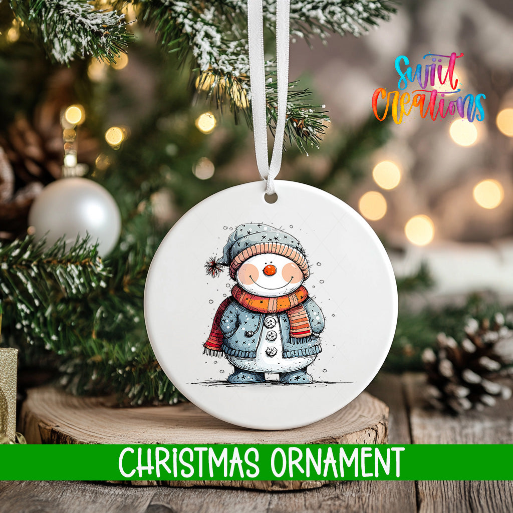 A white Christmas ornament featuring a snowman is hanging from a tree branch, with a blurred background of lights and greenery.