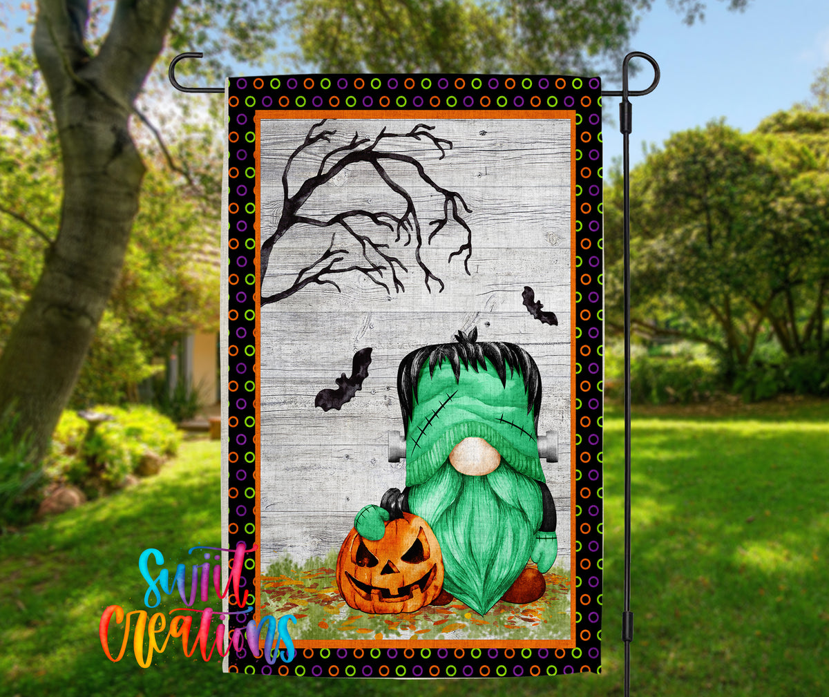 A Halloween-themed garden flag featuring a green gnome holding a carved pumpkin, with a spooky tree and bats in the background.