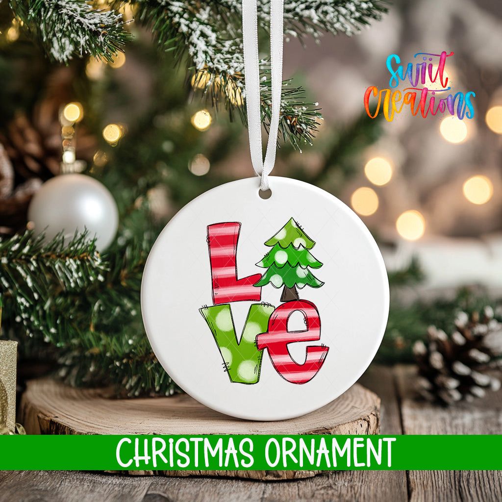 A white Christmas ornament with the word "LOVE" written on it, hanging on a tree branch.