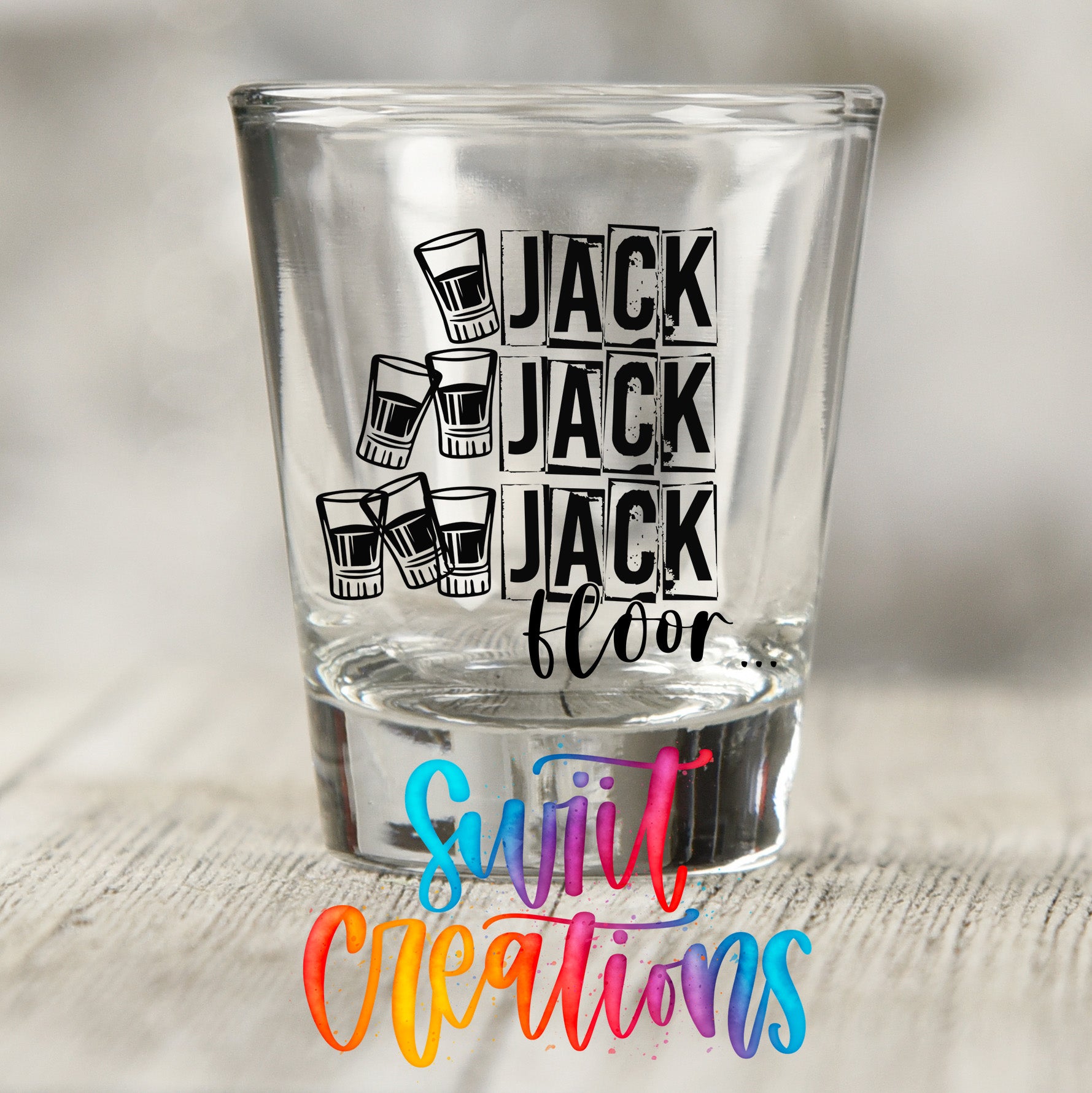 A shot glass with the text "JACK FLOOR" printed on it, along with illustrations of glasses.