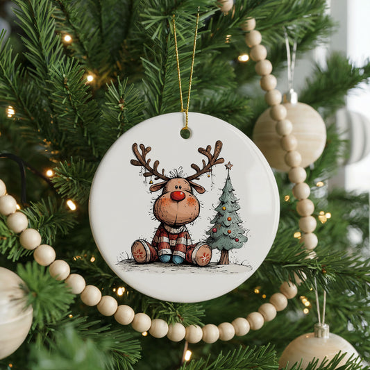 Sitting Reindeer Beside Christmas Tree ceramic Christmas ornament, front view