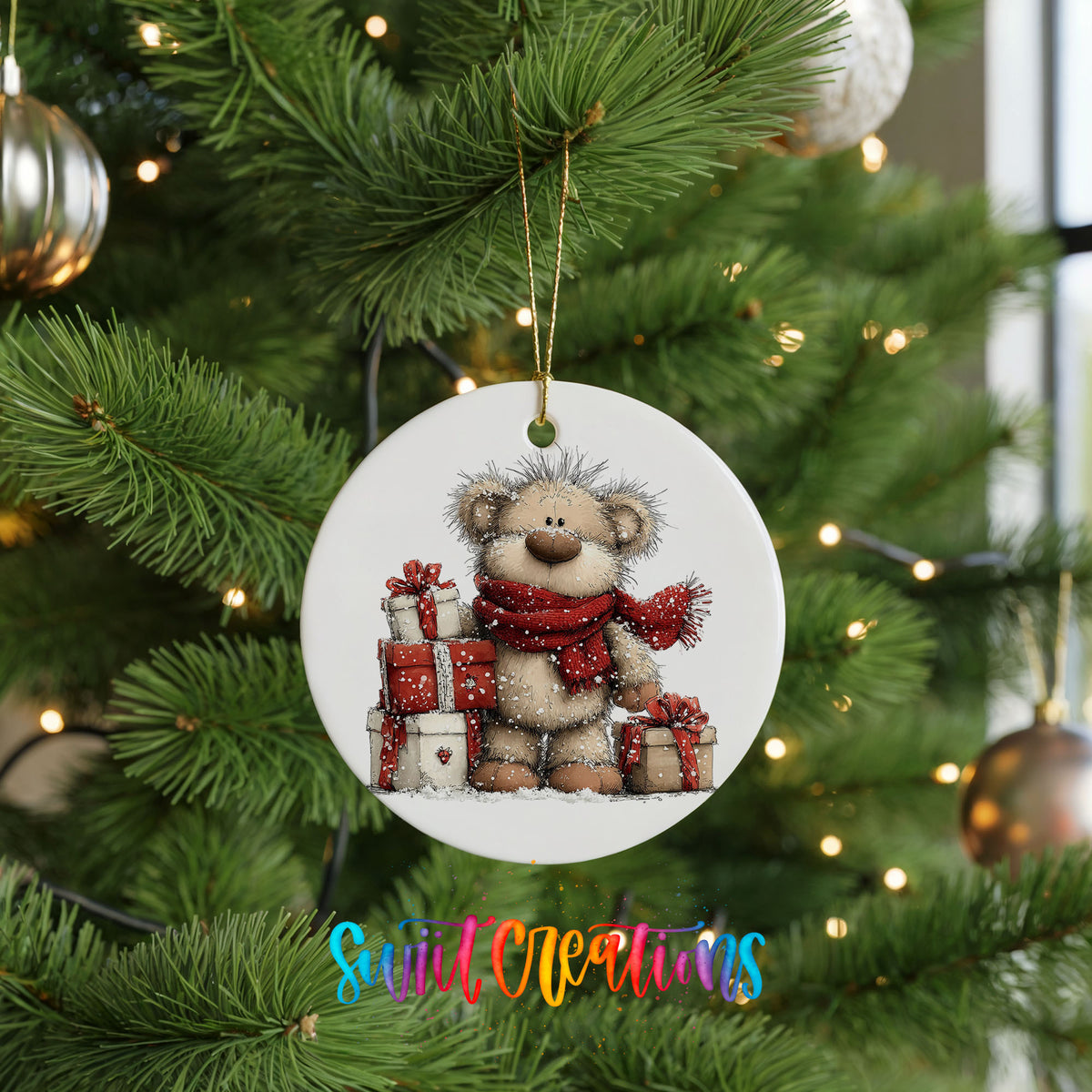 teddy bear with a red scarf and Christmas gifts ceramic Christmas ornament hanging on a lit Christmas tree