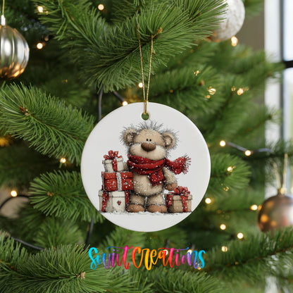teddy bear with a red scarf and Christmas gifts ceramic Christmas ornament hanging on a lit Christmas tree