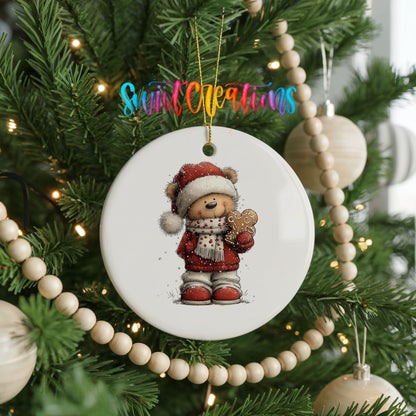 teddy bear in a Santa hat holding a gingerbread cookie ceramic Christmas ornament hanging on a green Christmas tree