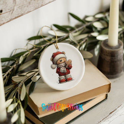 teddy bear in a Santa hat holding a gingerbread cookie ceramic Christmas ornament styled on stacked books with greenery
