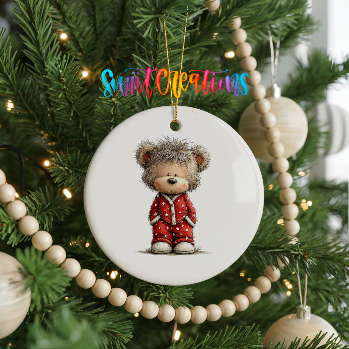 teddy bear wearing red Christmas pajamas ceramic Christmas ornament hanging on a green Christmas tree